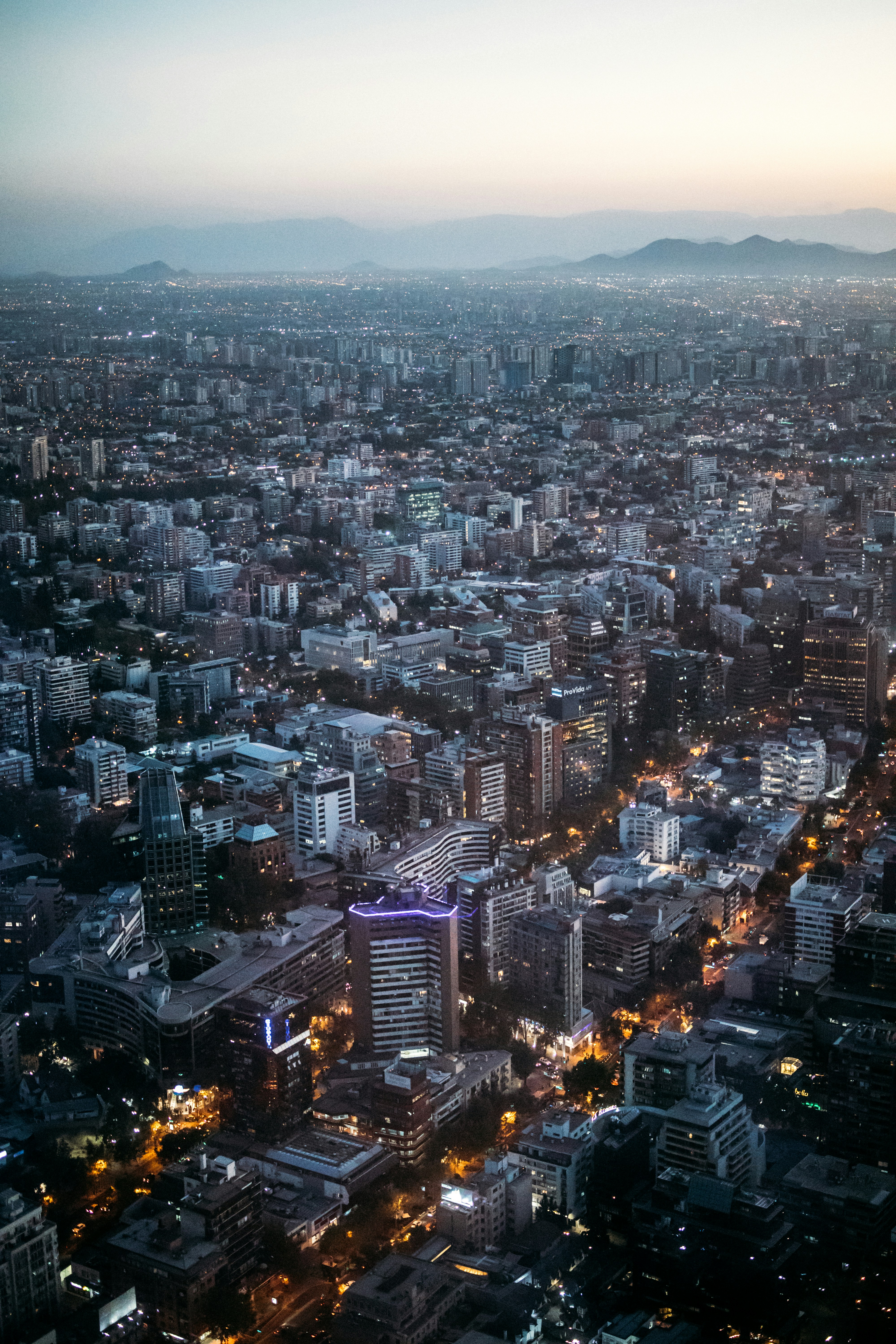 Panoramic City View At Twilight With Illuminated Buildings And Mountains. HD mobile wallpaper