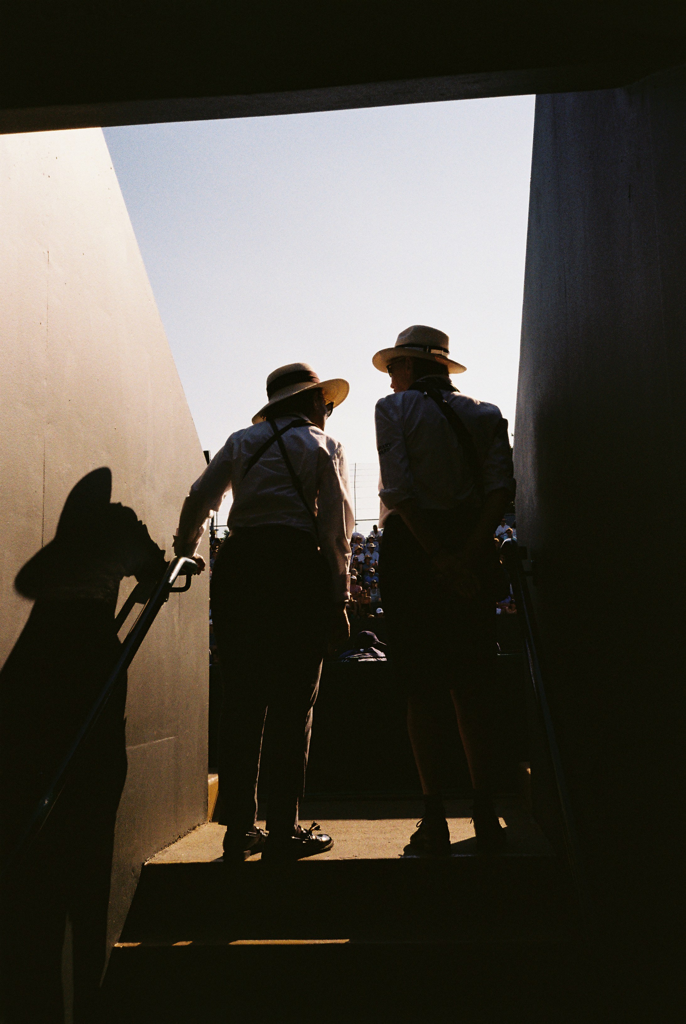 Two Straw-hatted Stewards Stand Silhouetted At A Gangway Exit As Bright Daylight Floods The Stairwell. HD mobile wallpaper