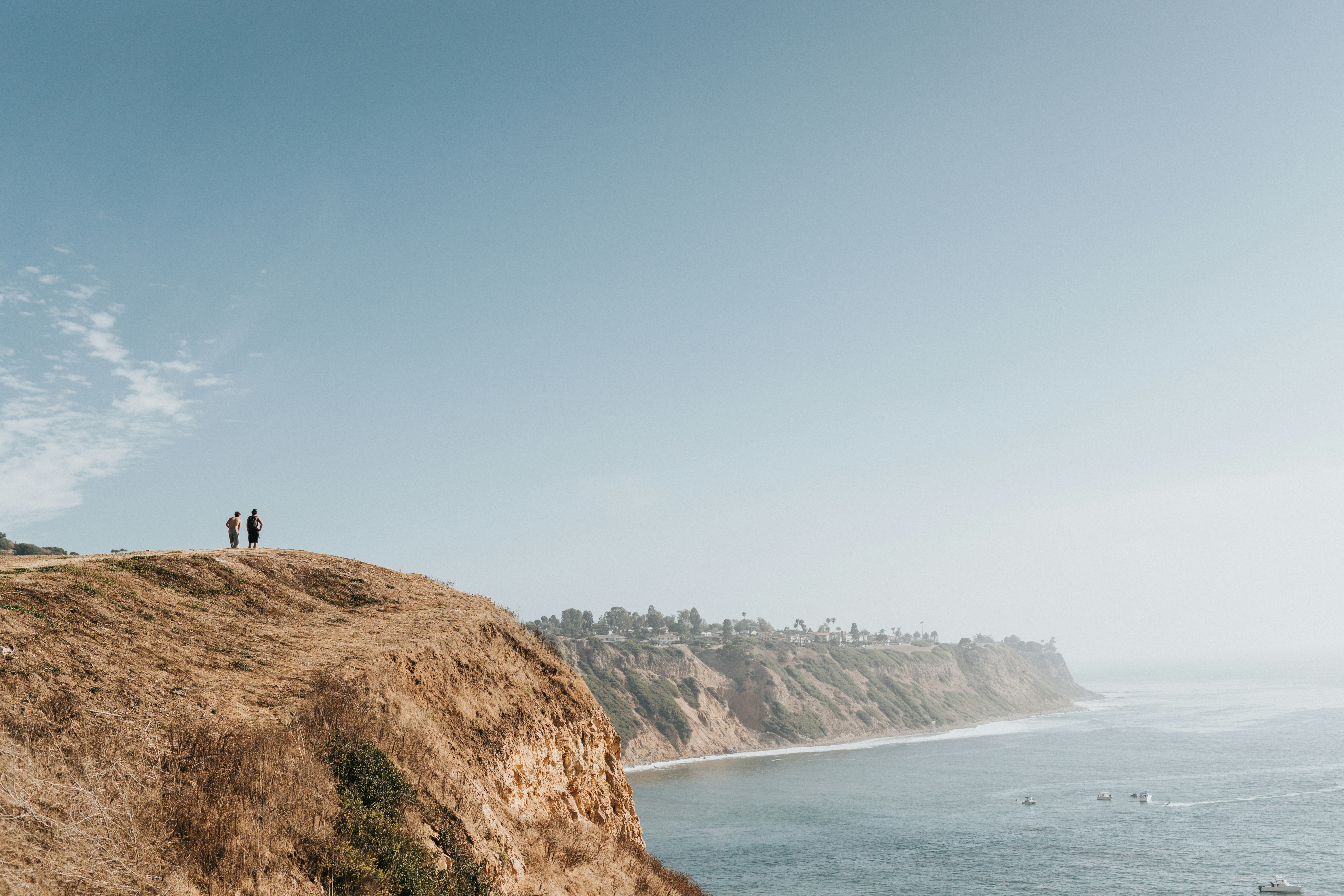 Two People Stand On A Grassy Cliff Overlooking The Ocean. HD mobile wallpaper