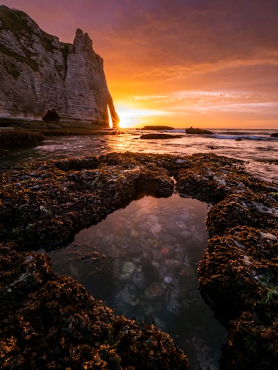 Vibrant Sunset Illuminates A Rocky Arch And Tide Pools. wallpaper preview