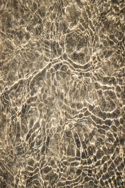 Rippling Water Creating Light Patterns On A Sandy Surface. wallpaper preview