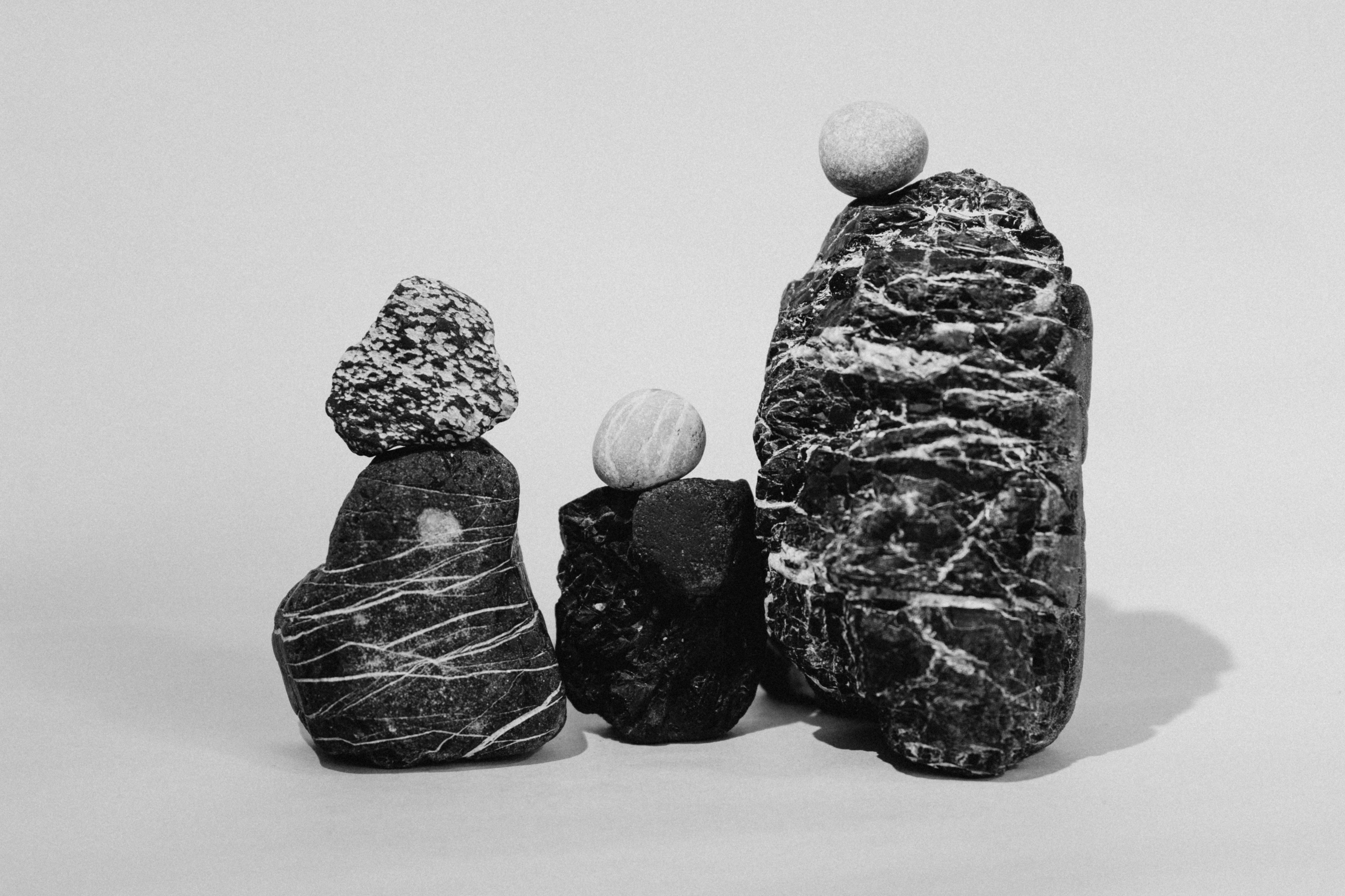 Three Stacks Of Balanced Rocks Against A Plain Background. HD mobile wallpaper