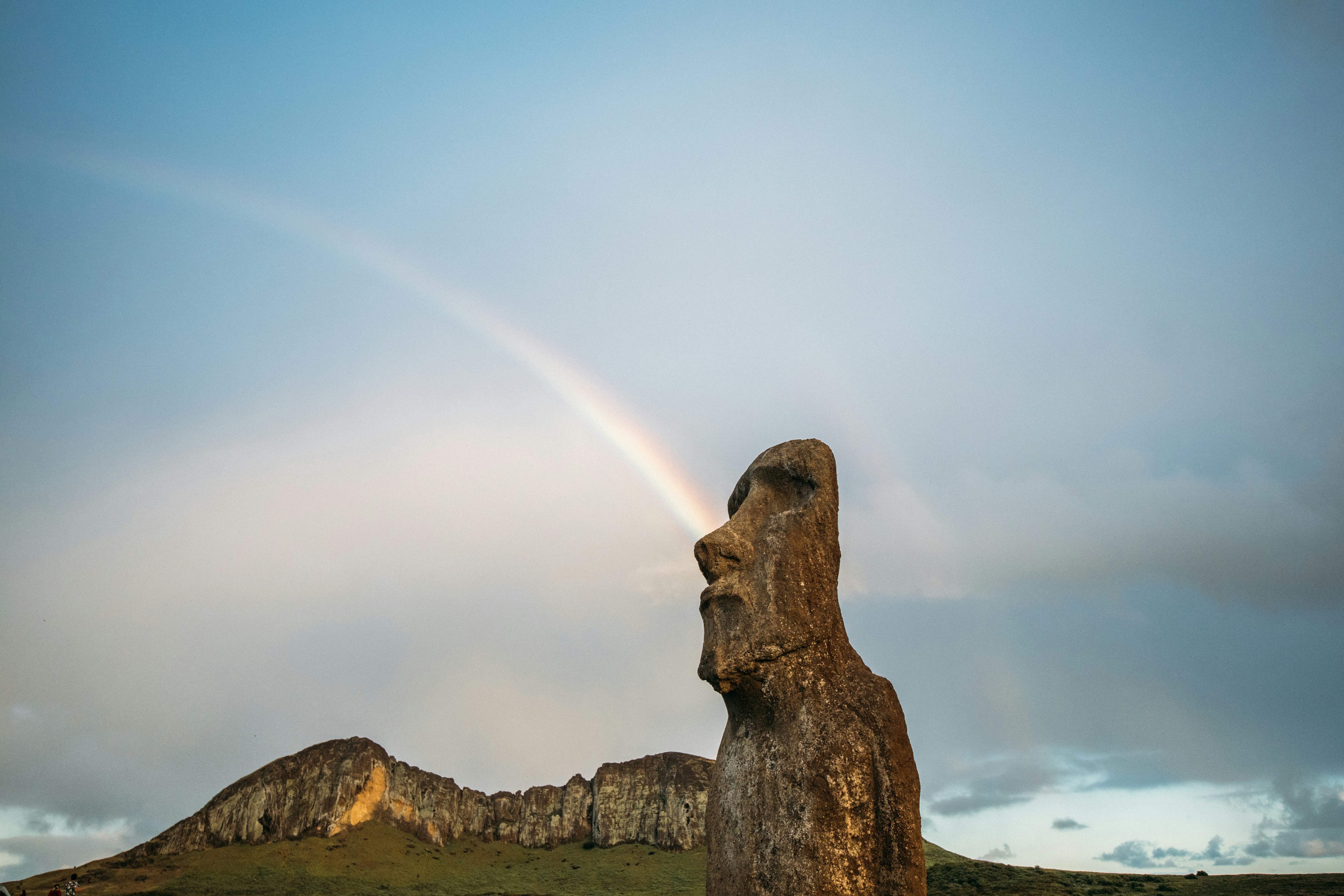 Rainbow Arches From A Moai Statue Against A Cloudy Sky. HD mobile wallpaper