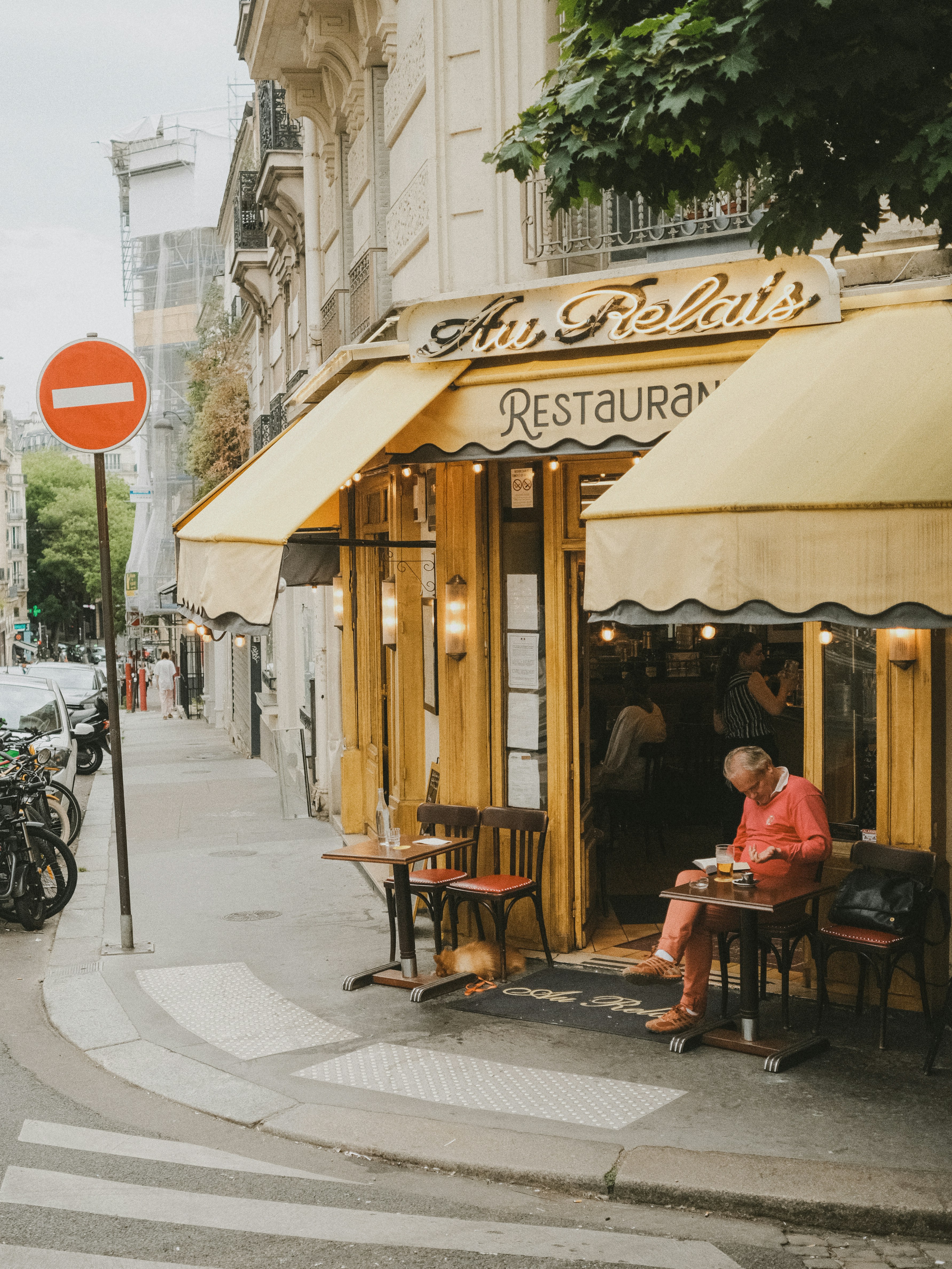 Man Dines Outside A Charming Yellow Restaurant In A City. HD mobile wallpaper