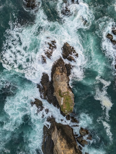 Rugged Rocks Surrounded By Foamy Turquoise Ocean Waves. wallpaper preview