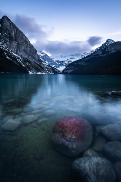 Clear Mountain Lake, Snow-capped Peaks, And A Red Rock. wallpaper preview