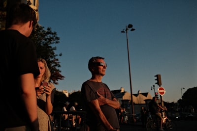 A Man Wearing Solar Eclipse Glasses On A City Street At Golden Hour. wallpaper preview