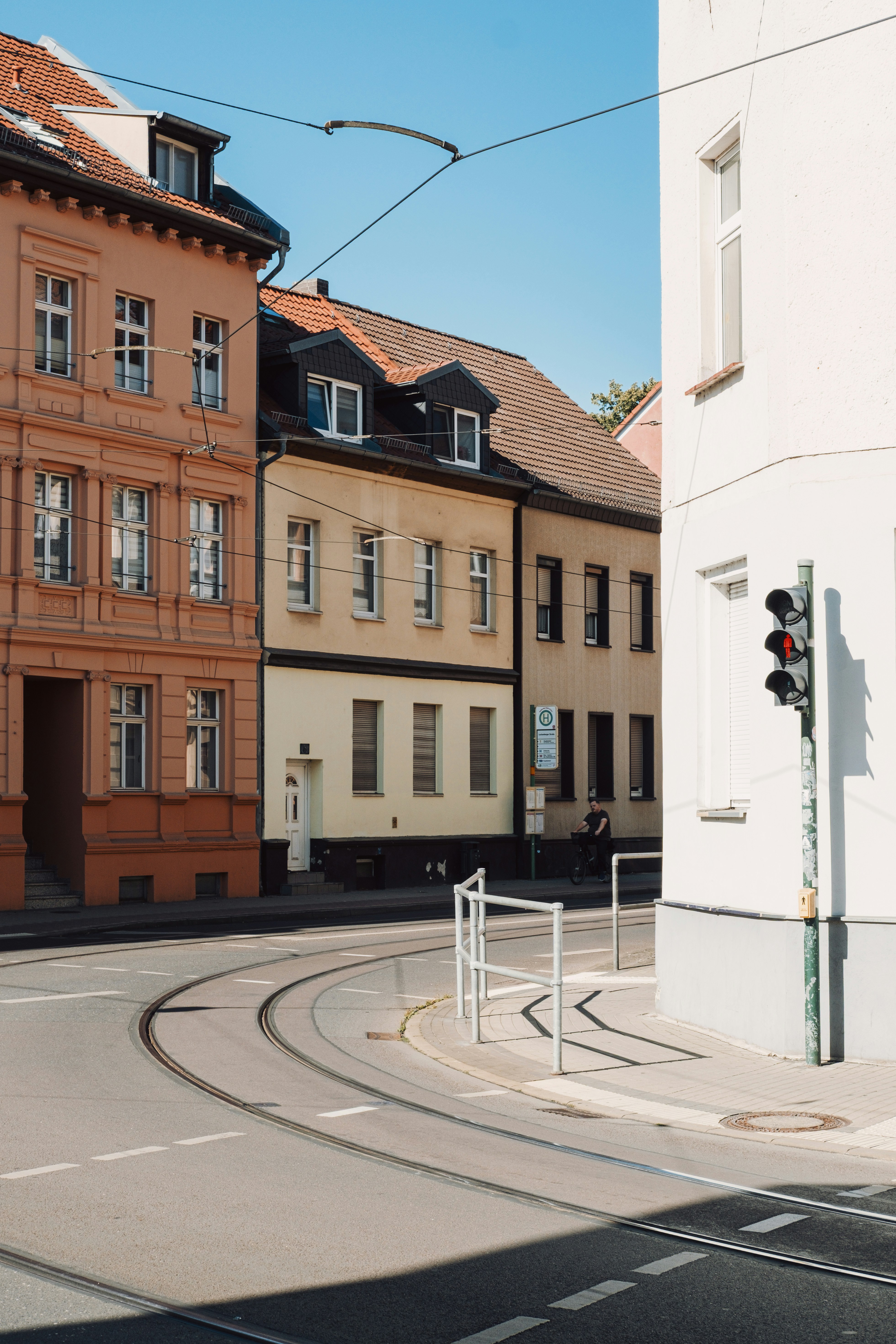 A Person Cycling Past Colorful Buildings And Tram Tracks In Brandenburg, Germany HD mobile wallpaper