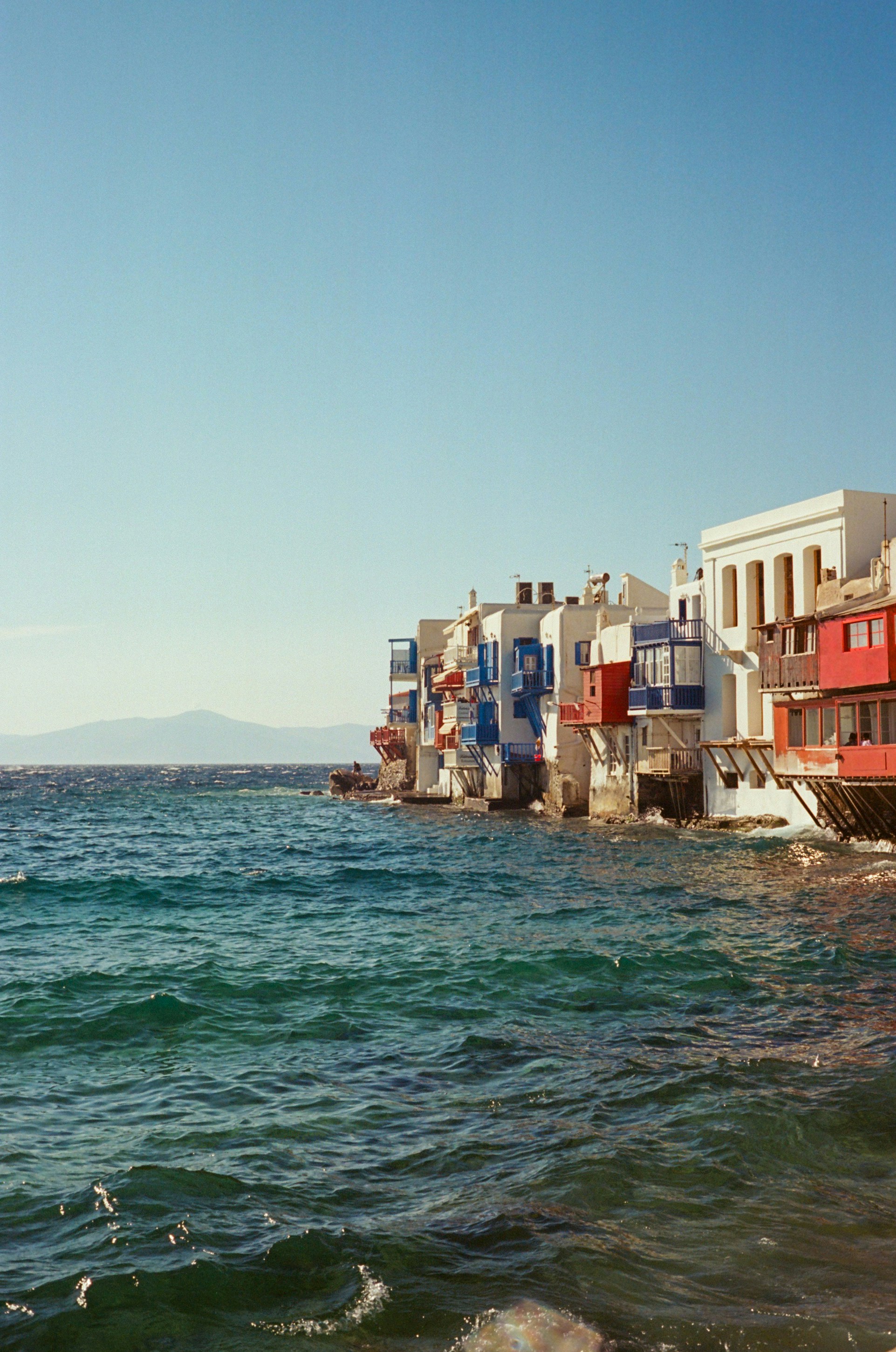 Colorful Buildings Line The Wavy Blue Sea Under Clear Sky. HD mobile wallpaper