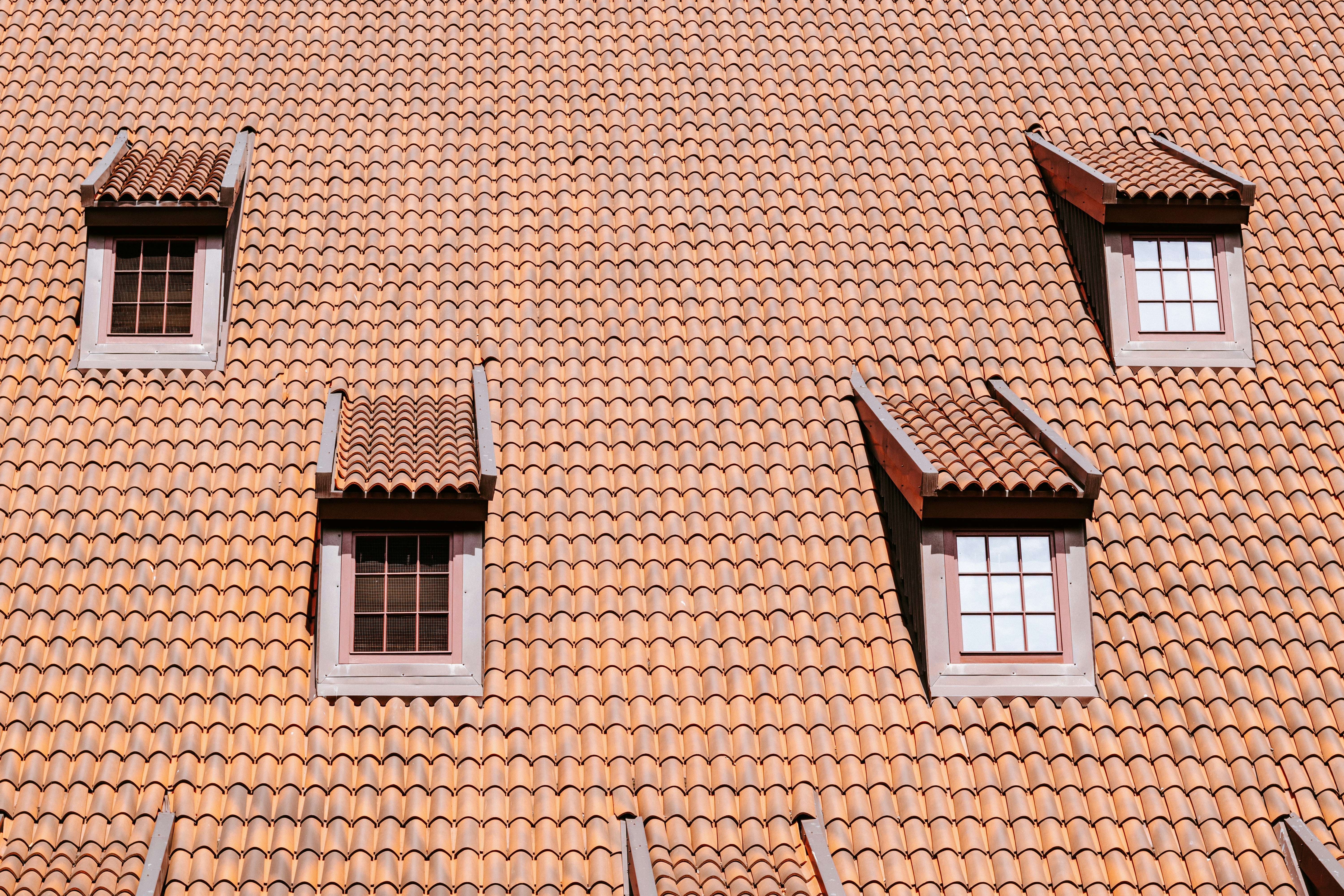 Four Dormer Windows Set Into A Sloping Roof Covered In Orange Clay Tiles HD mobile wallpaper