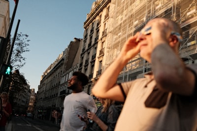 People On A Street In Paris Looking Up At The Sky During Golden Hour.