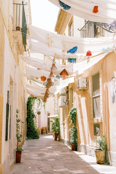A Narrow Stone Alleyway Shaded By White Fabric Canopies And Hanging Woven Lanterns wallpaper preview