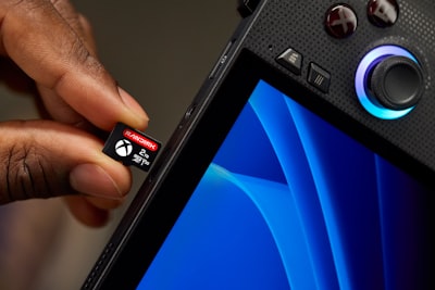 Hand Inserting Xbox Memory Card Into Portable Gaming Device. wallpaper preview
