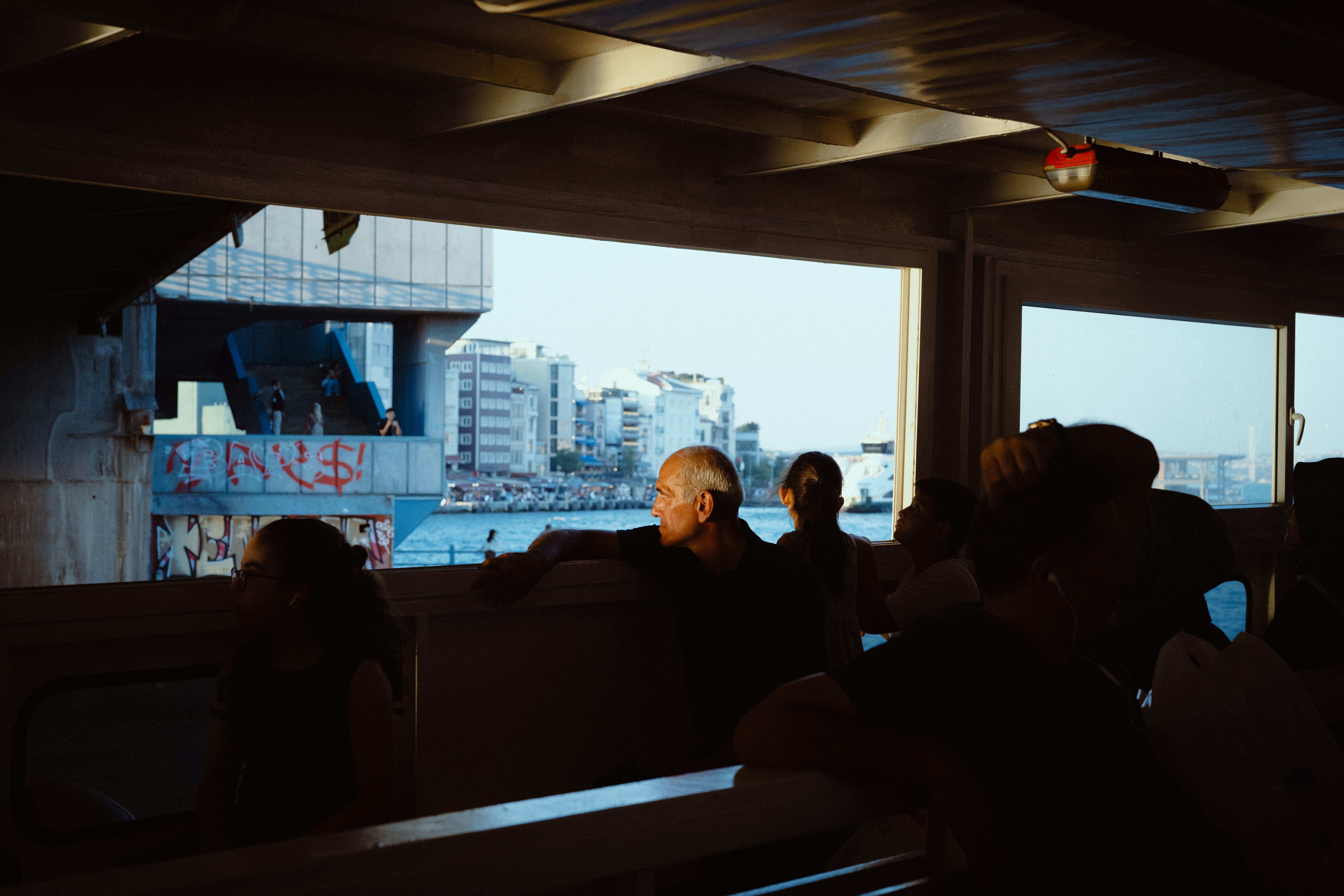 People Looking Out From A Ferry Window At A City Waterfront With Graffiti HD mobile wallpaper