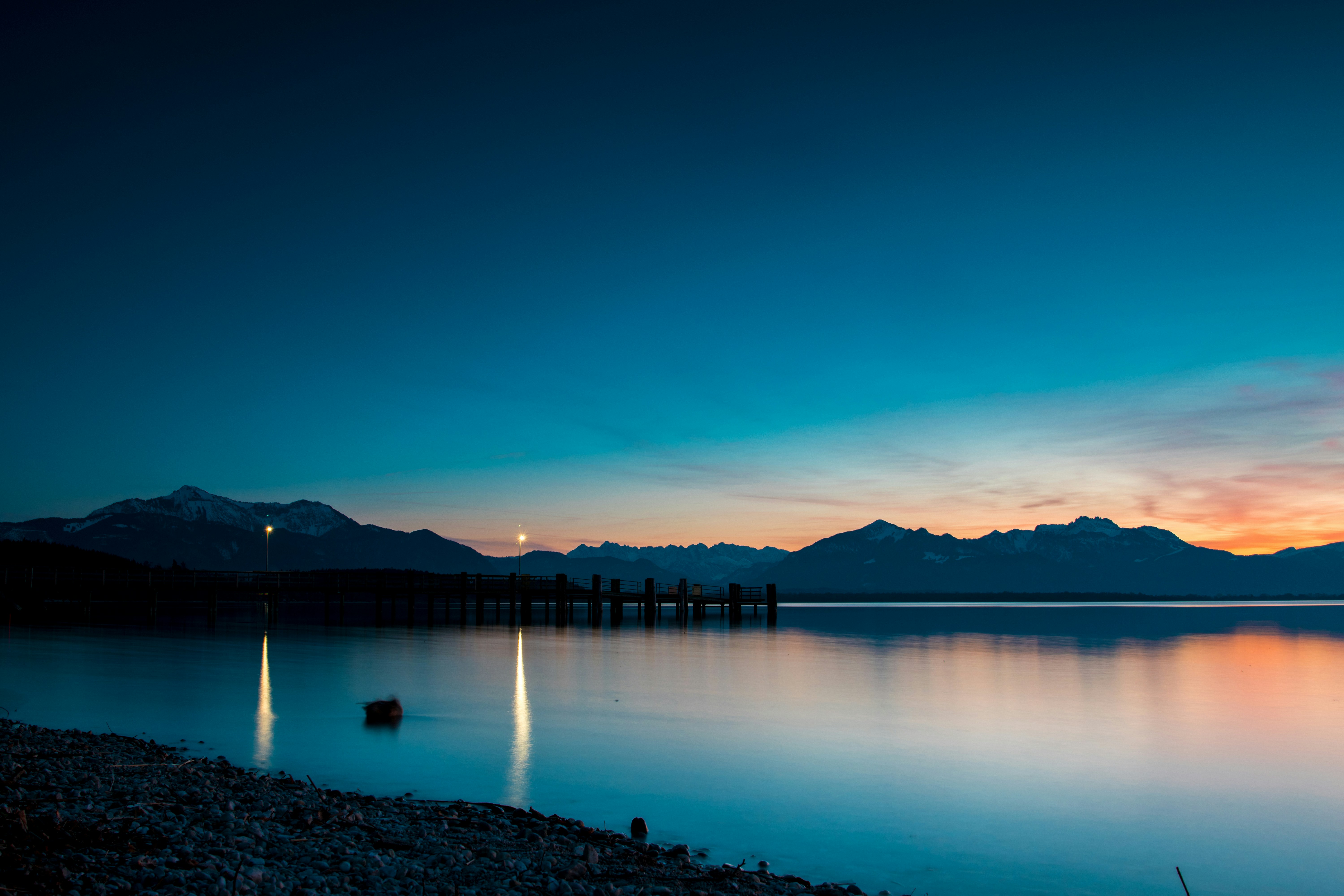 A Wooden Pier Extending Into A Calm Lake Beneath A Colorful Sky At Dusk HD mobile wallpaper
