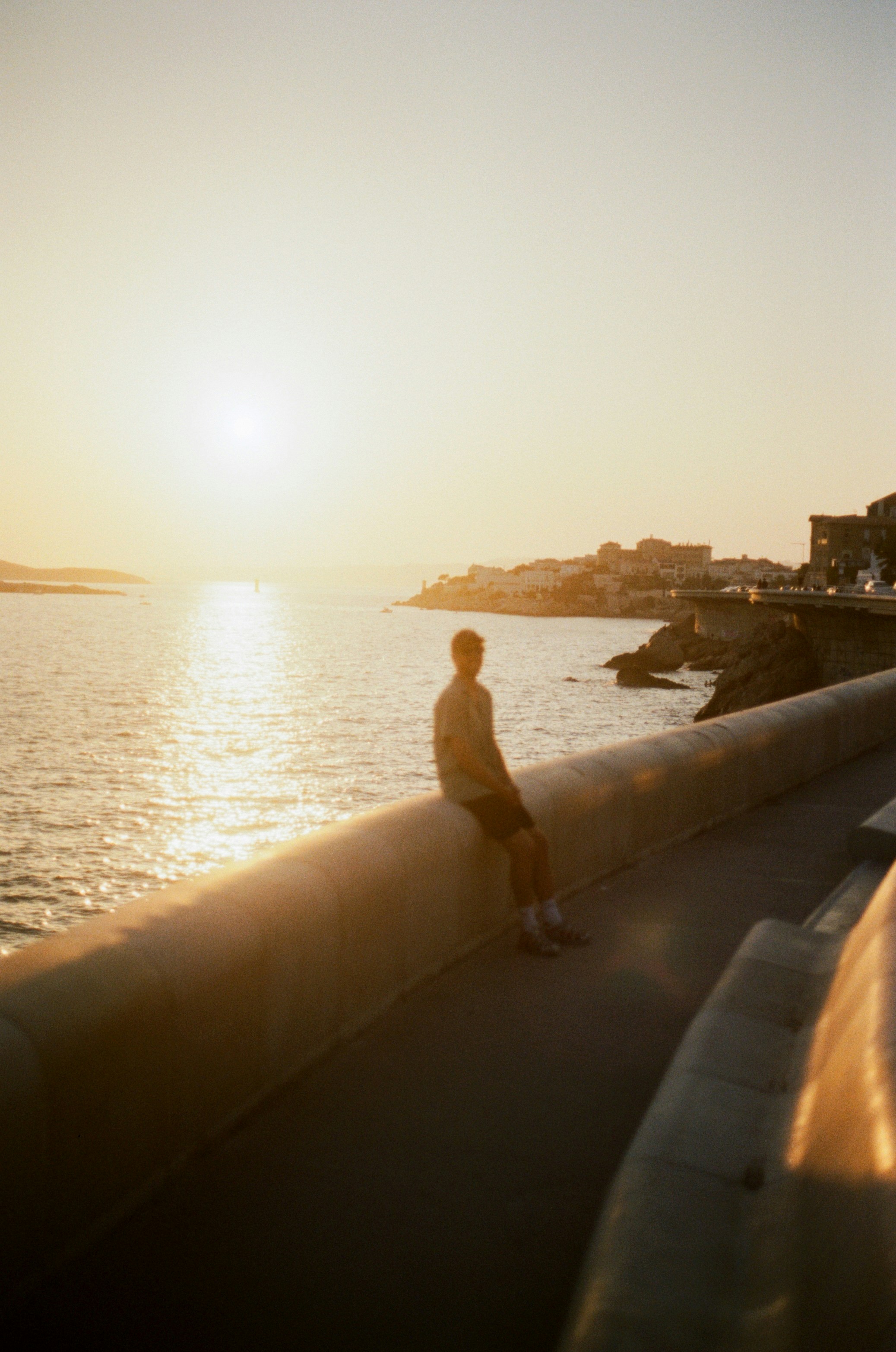 A Person In Silhouette On A Concrete Wall Overlooking The Sea At Low Sun HD mobile wallpaper