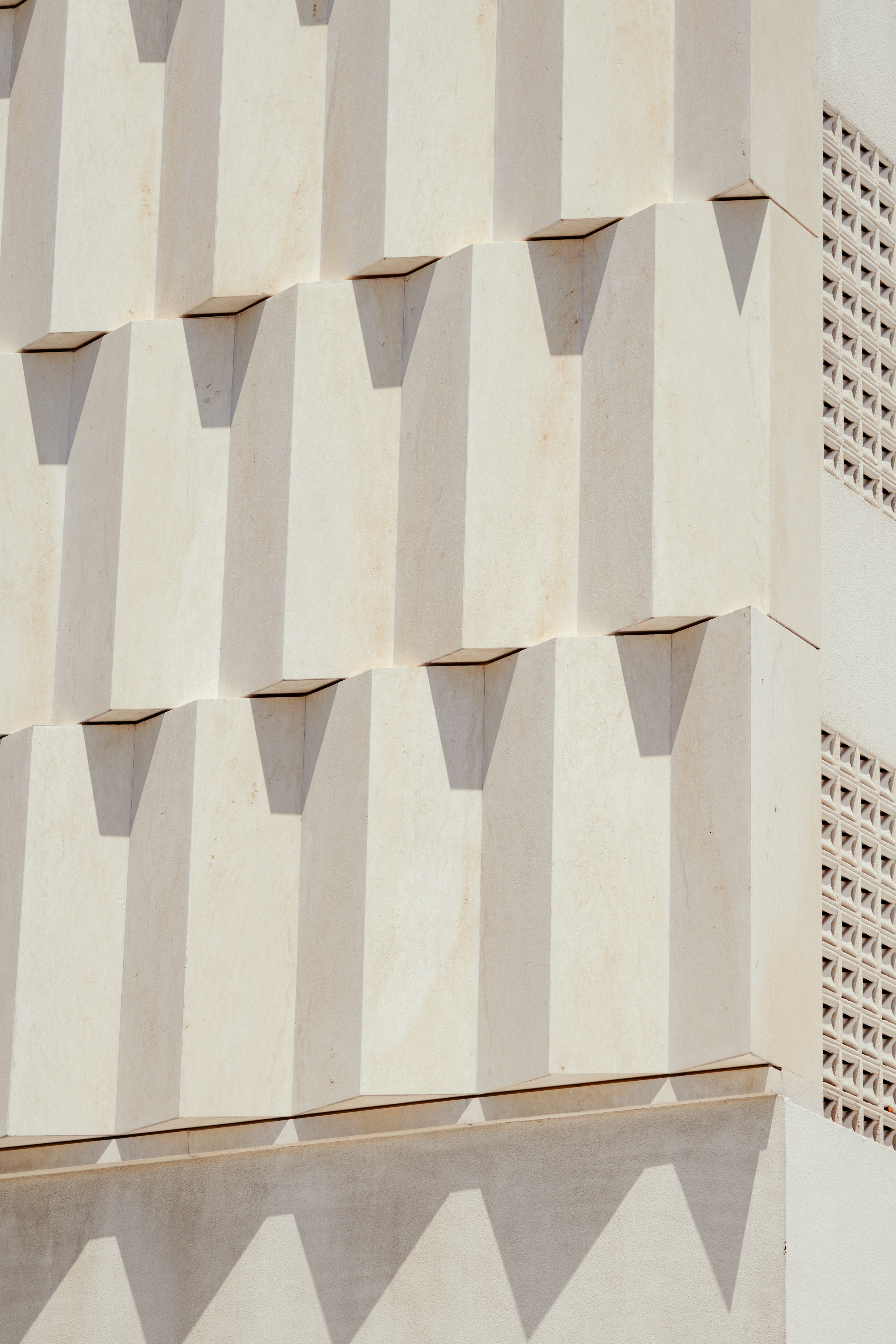 A White Building Facade With Geometric Protruding Blocks And A Decorative Lattice Screen HD mobile wallpaper