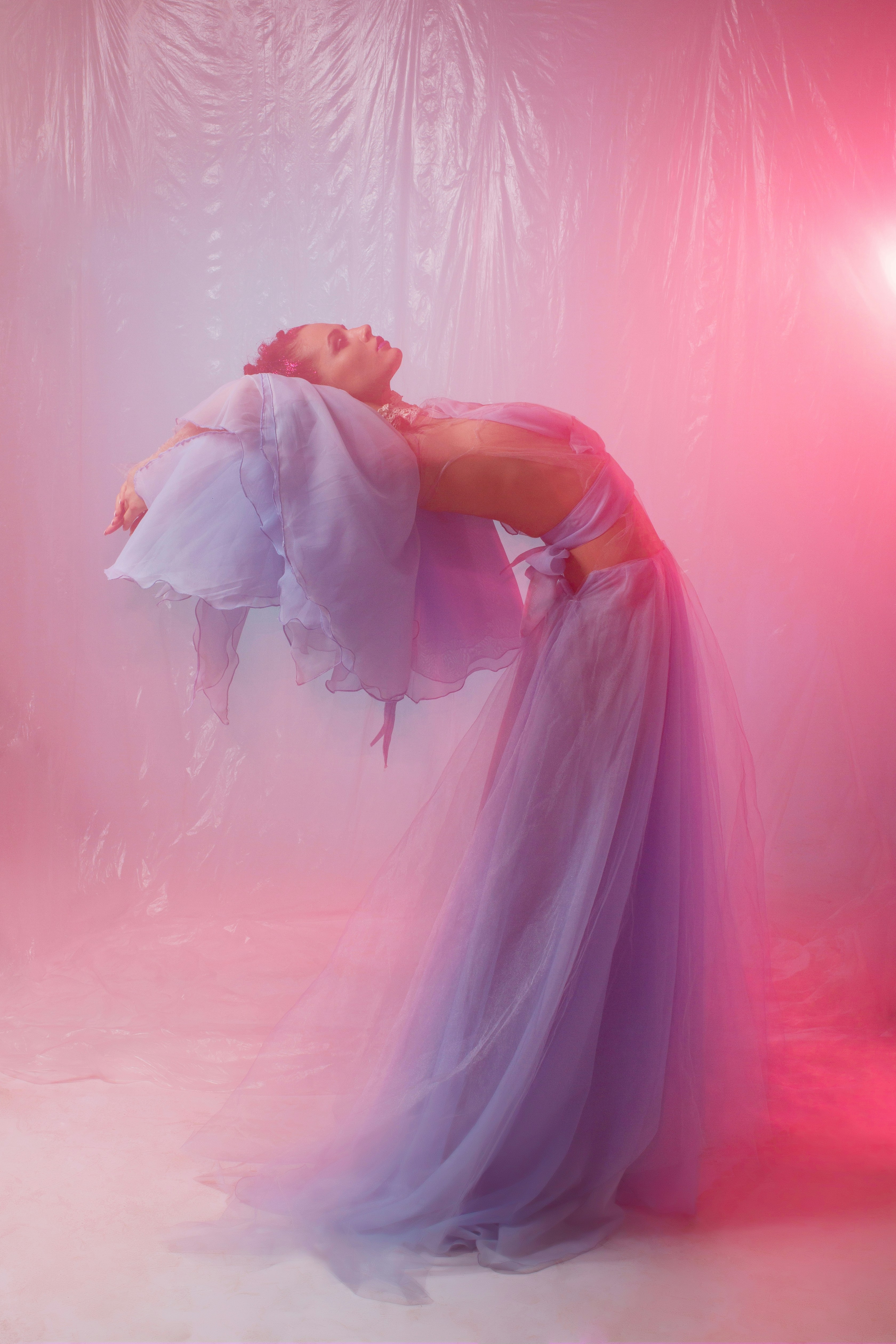 A Woman In A Flowing Purple Dress Arching Backward Against A Pink Plastic Background HD mobile wallpaper