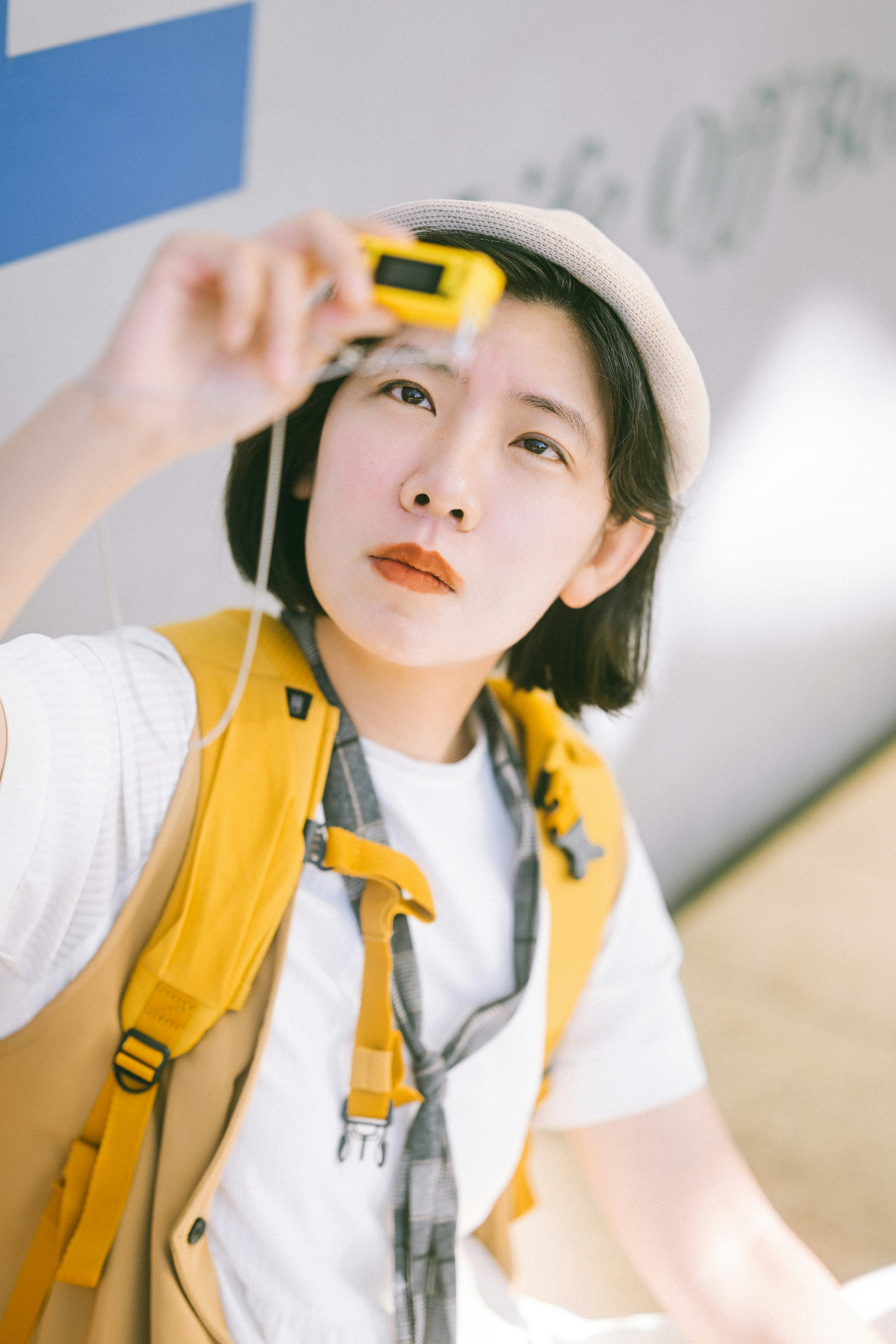 A Person In A White Shirt And Yellow Backpack Looking Through A Small Camera HD mobile wallpaper