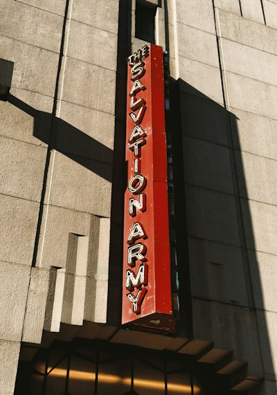 A Vertical Red Salvation Army Sign On A Stone Building Facade wallpaper preview