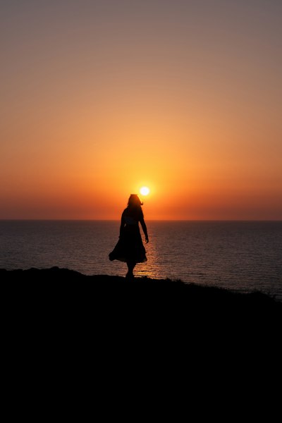 A Person In Silhouette Against A Warm Orange Sky Above The Ocean wallpaper preview