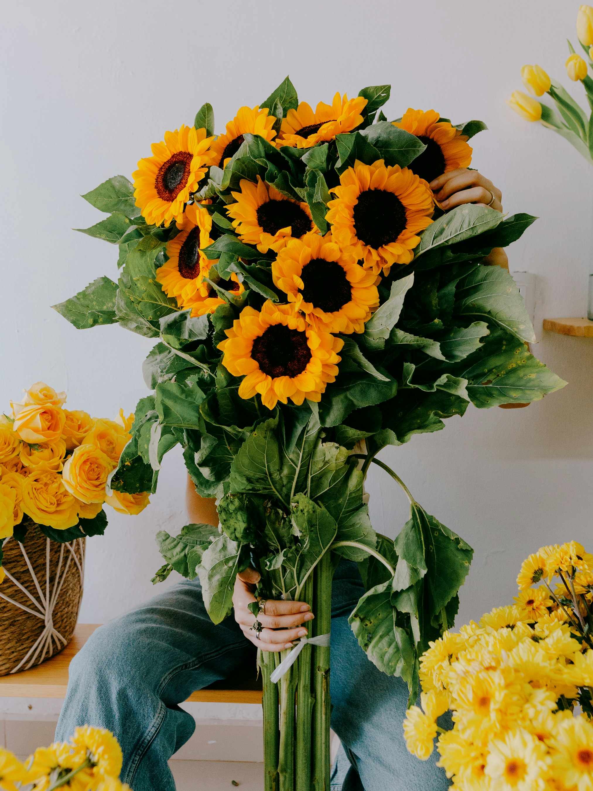 A Person Holding A Large Bouquet Of Sunflowers In Front Of Their Face HD mobile wallpaper