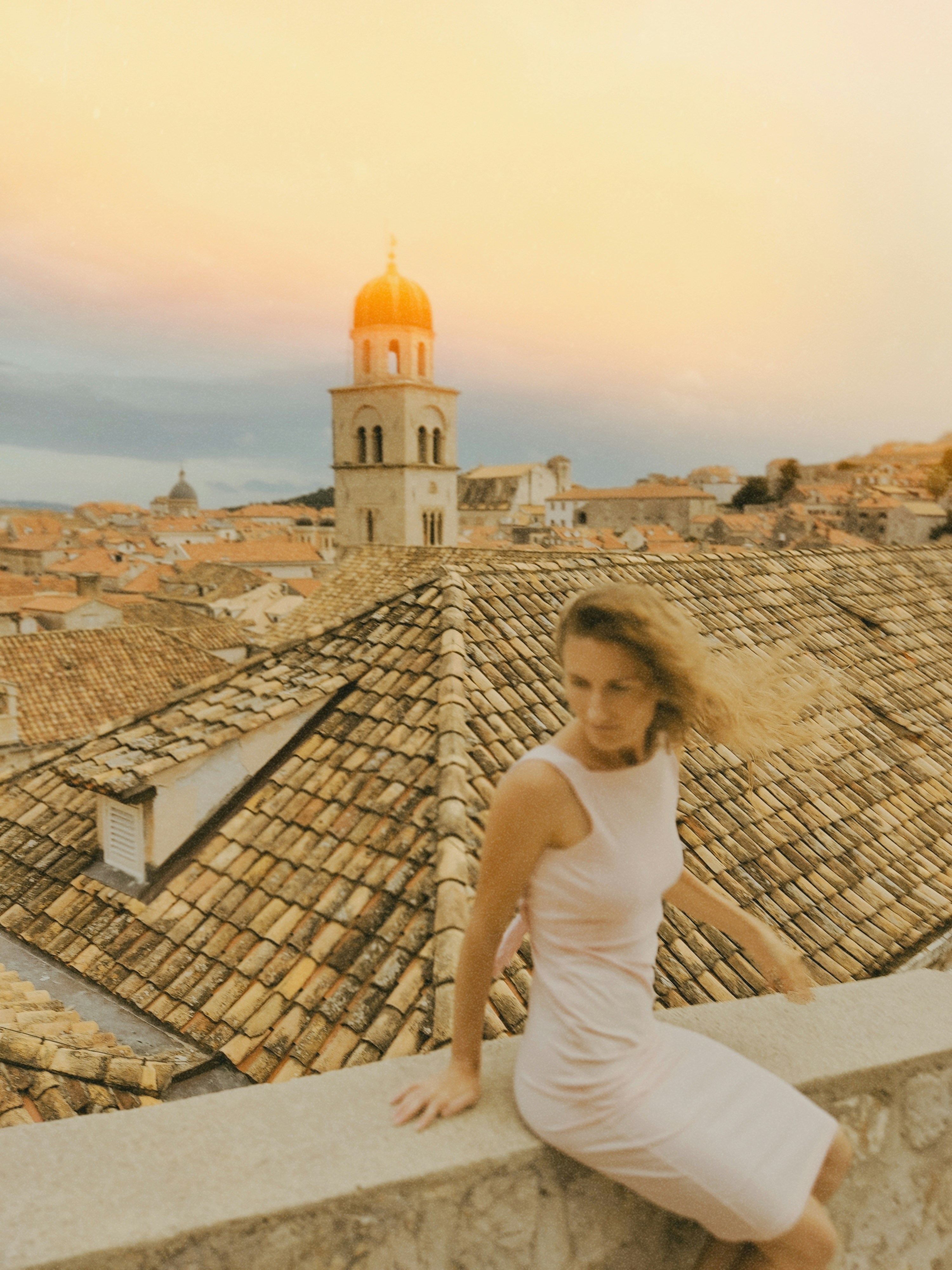 A Woman In A Light Dress Sitting On A Stone Wall Overlooking Dubrovnik Rooftops HD mobile wallpaper