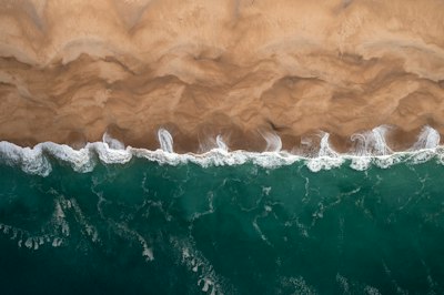 Aerial View Of Turquoise Ocean Waves Crashing Onto A Sandy Beach wallpaper preview