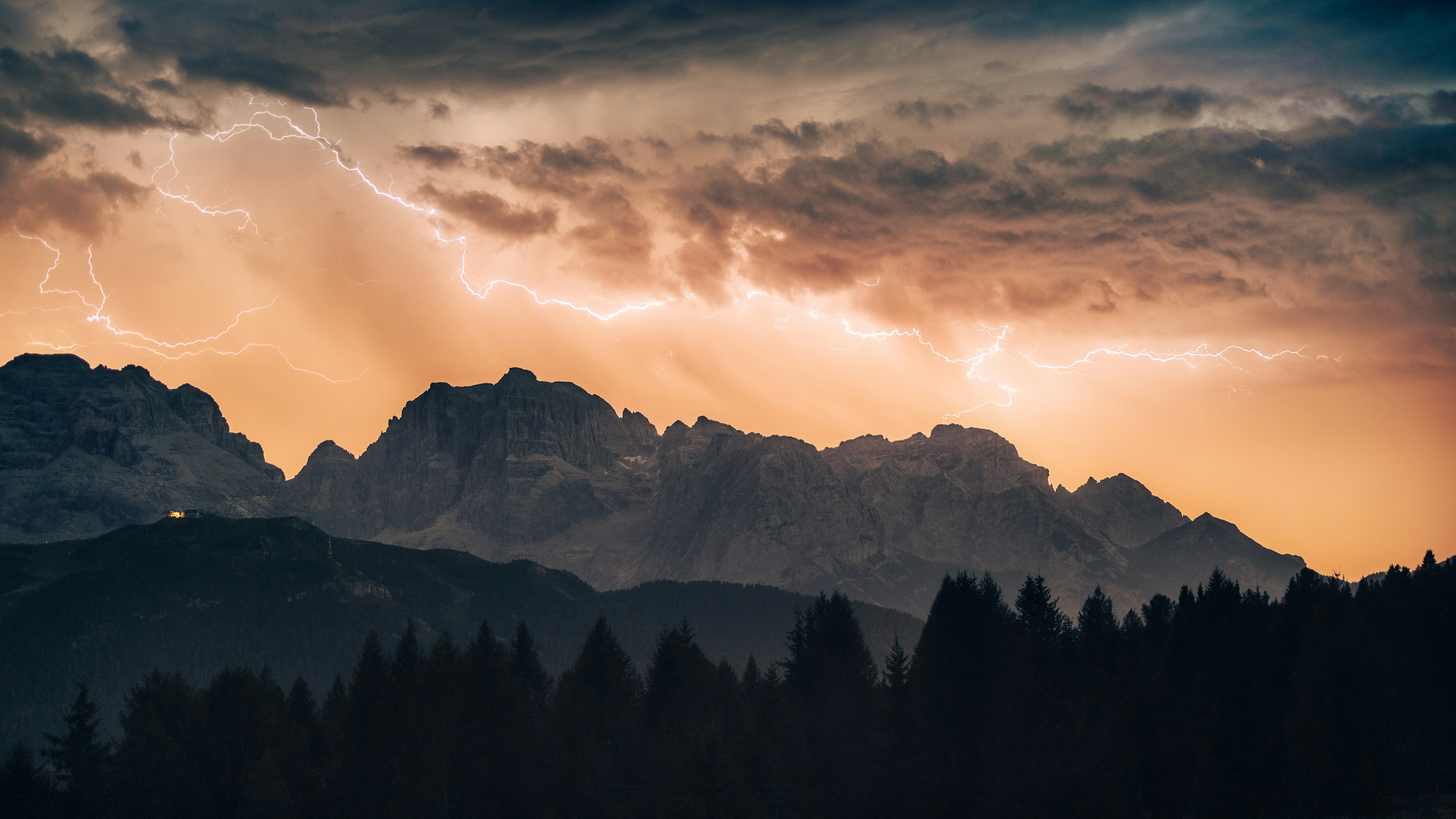 Lightning Bolts Across A Warm Orange Sky Above Dark Mountain Peaks And Pine Trees HD mobile wallpaper