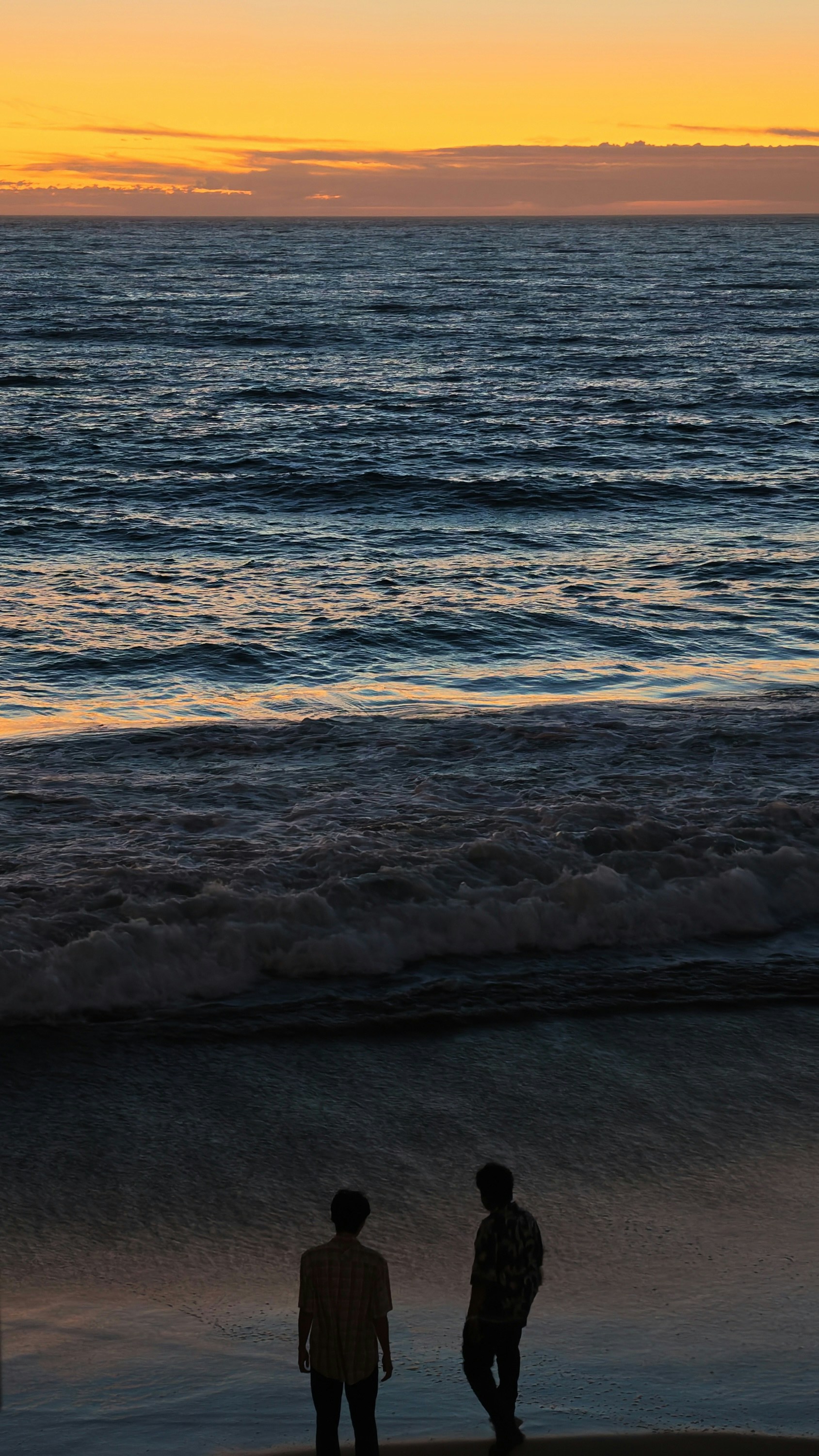 Two People In Silhouette On A Beach Under A Warm Orange Sky HD mobile wallpaper