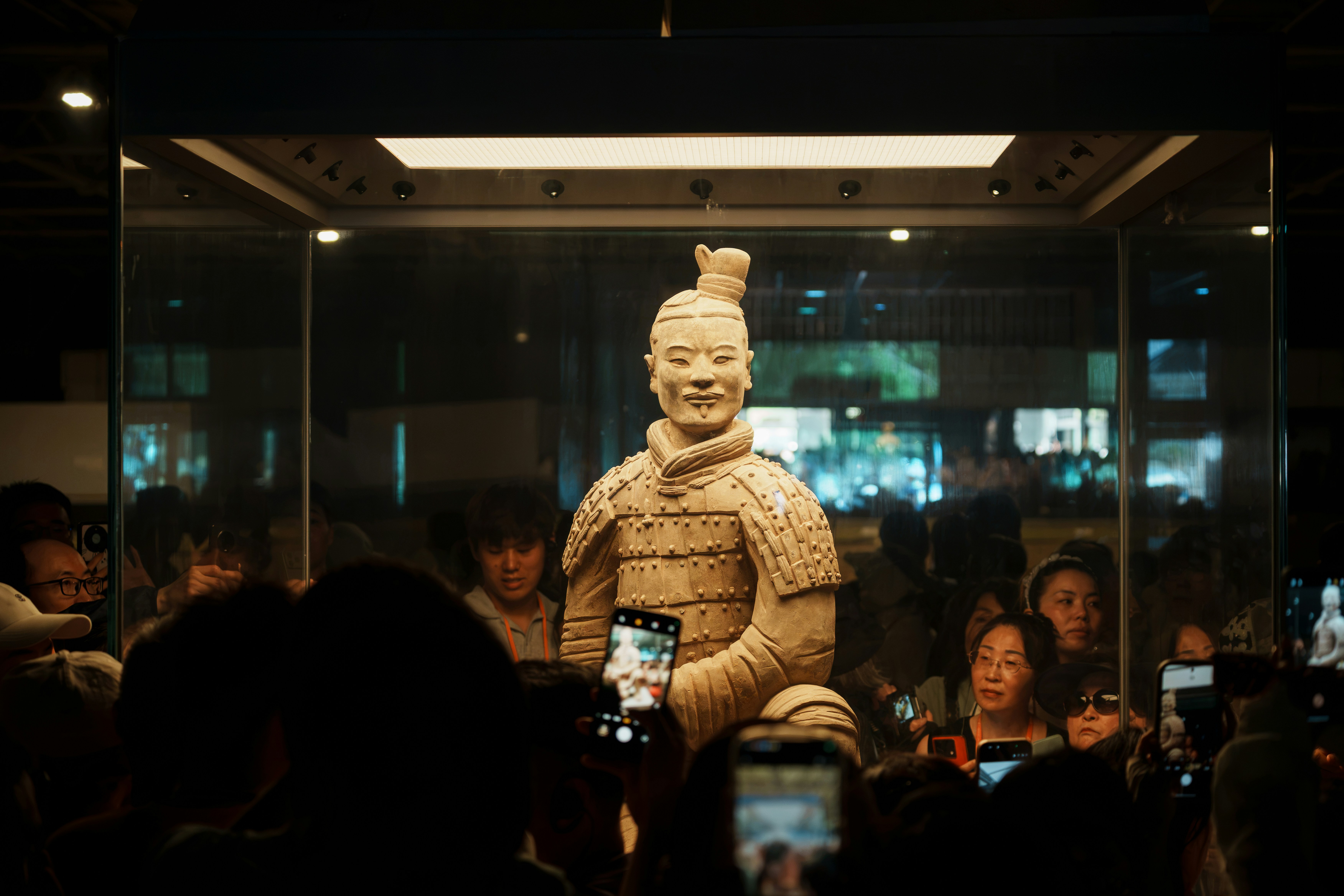 A Terracotta Warrior Statue Inside A Glass Display Case Surrounded By A Crowd HD mobile wallpaper