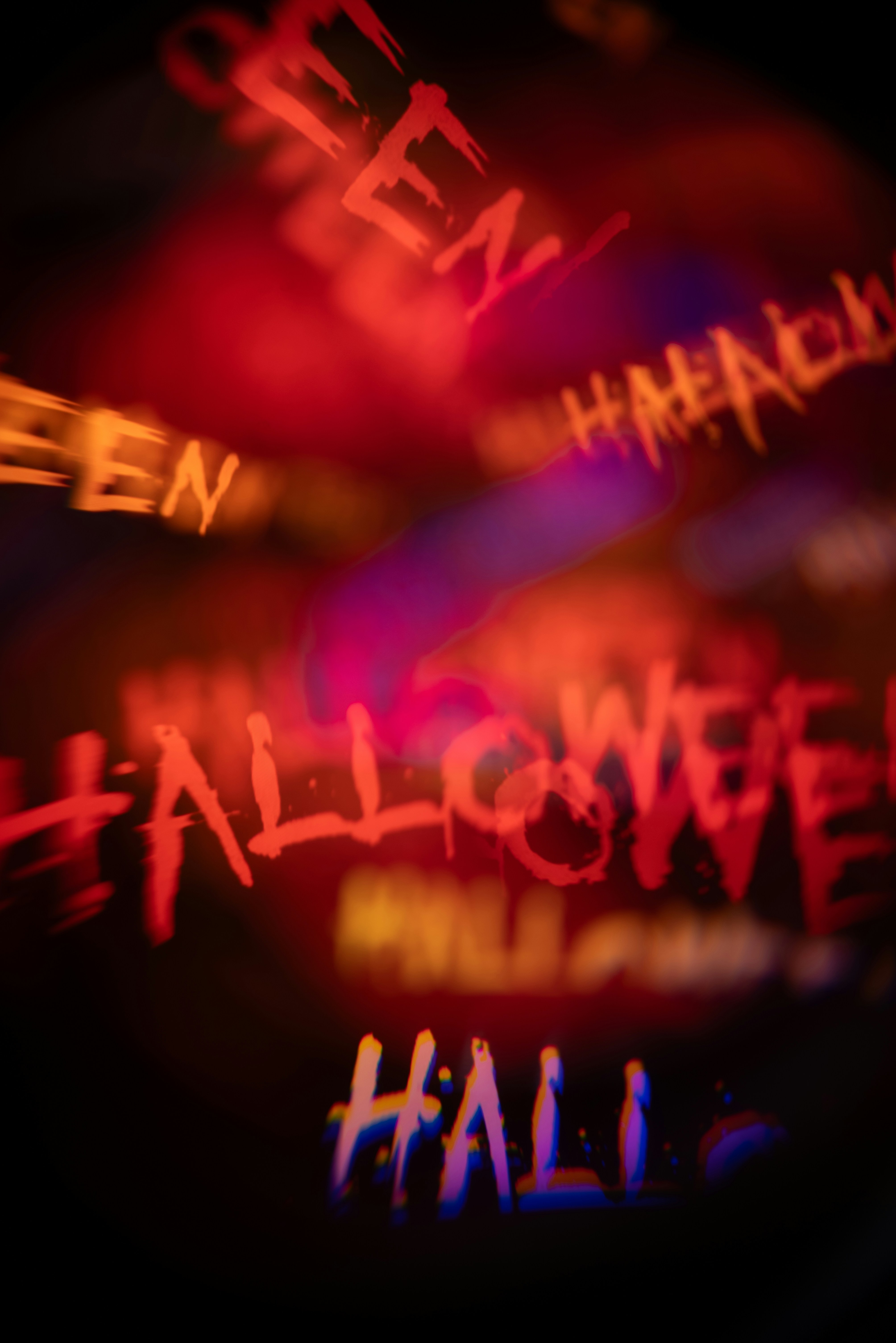 Blurred Red And Orange Text Reading Halloween Against A Dark Background With Chromatic Aberration HD mobile wallpaper