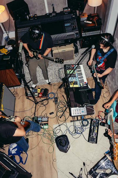 A Band Playing Instruments In A Recording Studio With Cables Scattered Across The Floor wallpaper preview