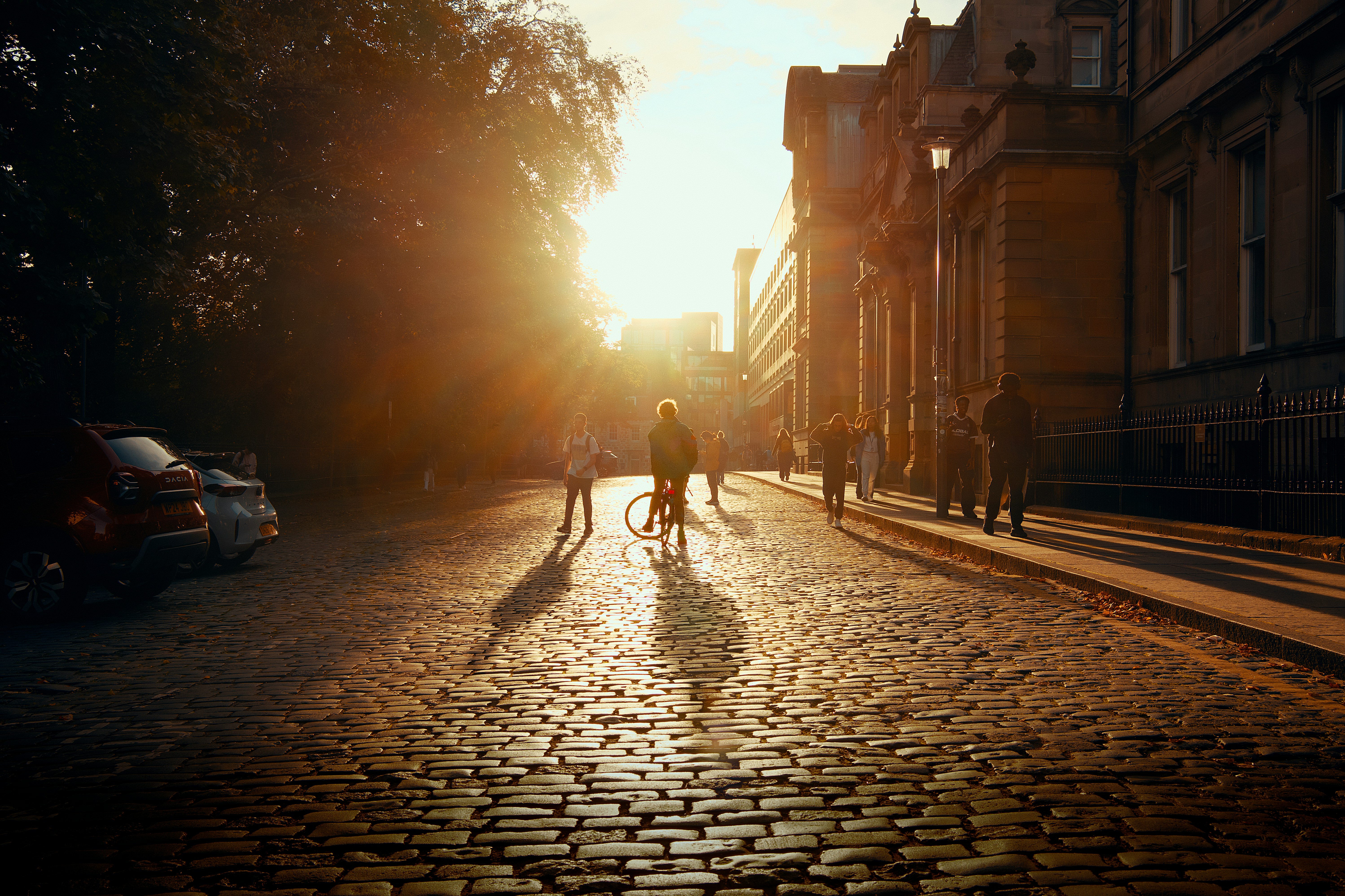 People Walking And Cycling On A Cobblestone Street During The Golden Hour HD mobile wallpaper