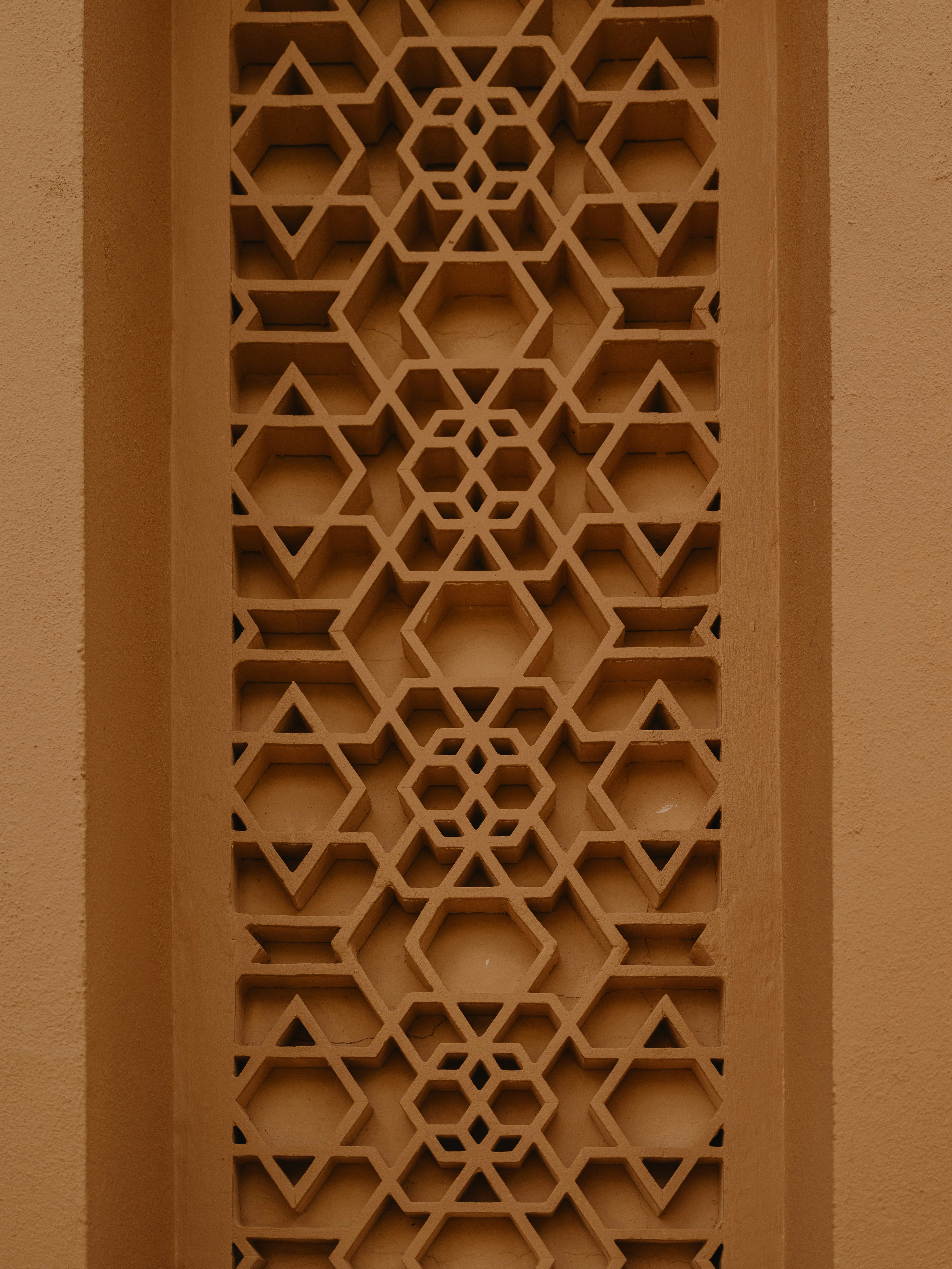 Close Up Of A Carved Geometric Lattice Screen At Masjid Tengku Ampuan In Kuala Lumpur, Showing Classic Islamic Star Patterns In Warm Sandstone. HD mobile wallpaper