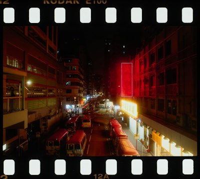 Red Minibuses On A City Street At Night With Glowing Neon Signs wallpaper preview