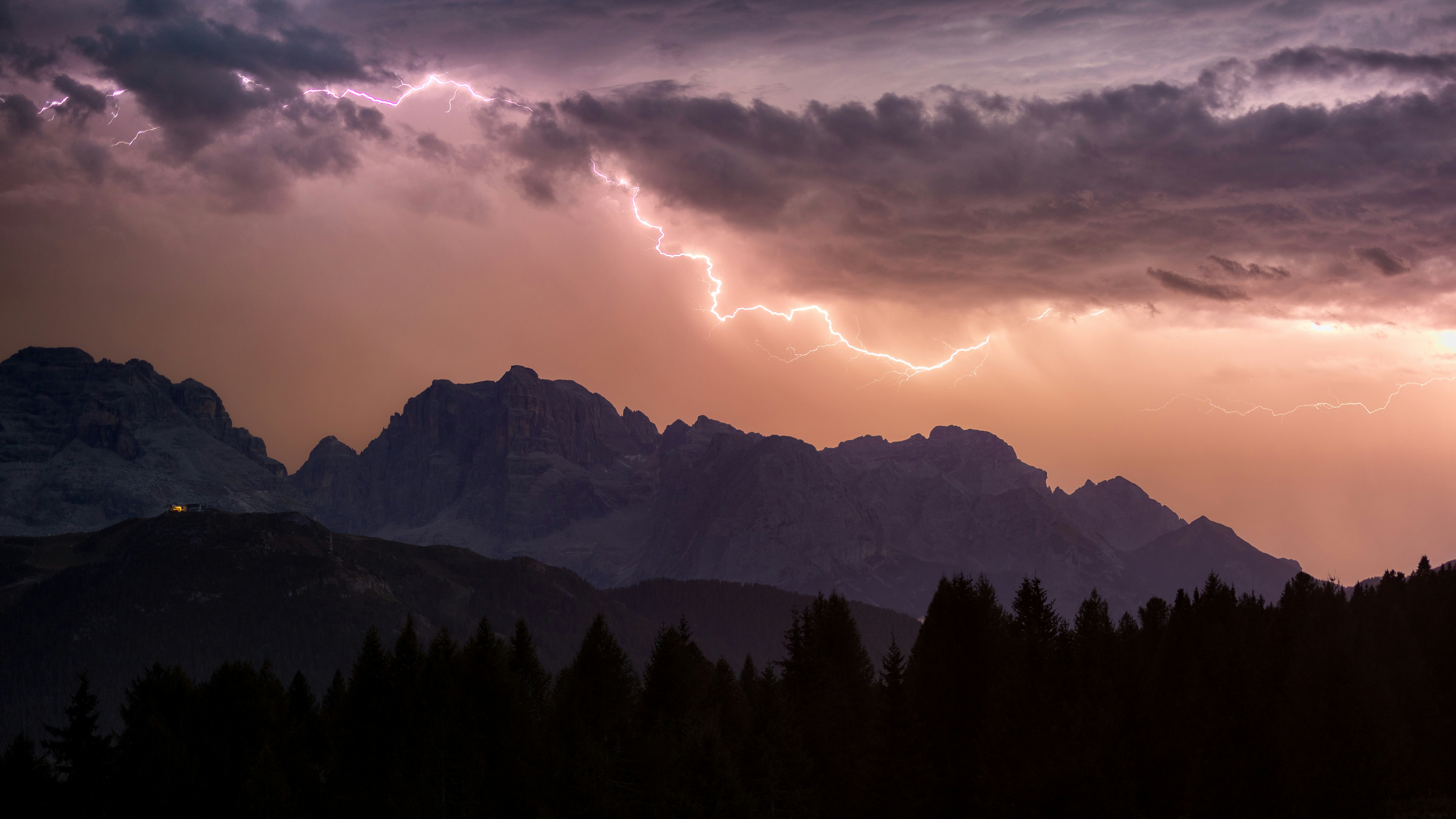 Lightning Striking Behind Dark Mountain Peaks Under A Purple And Orange Cloudy Sky HD mobile wallpaper