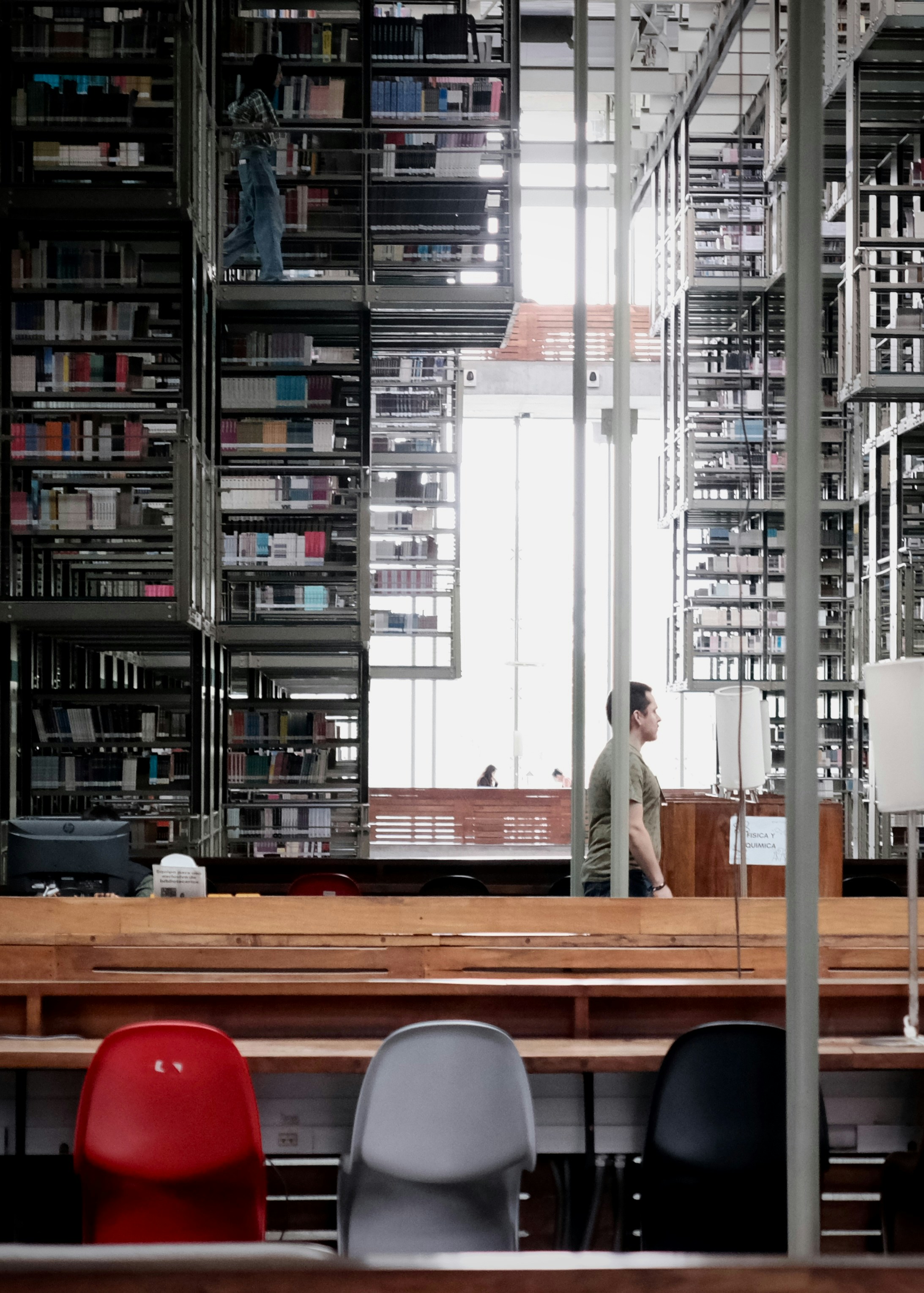 Man Sitting At Desk In Modern Library With Tall Bookshelves HD mobile wallpaper