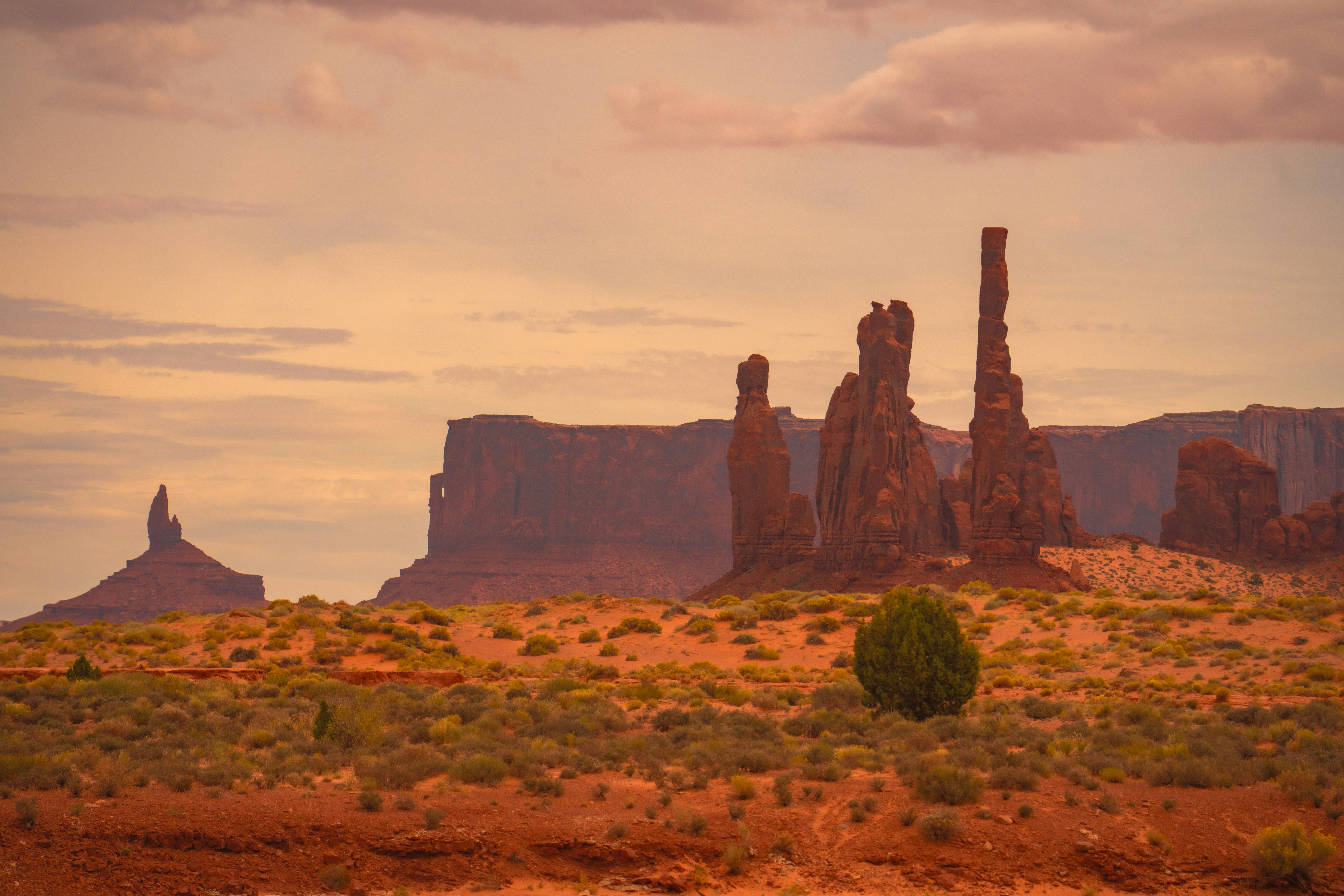 Red Sandstone Buttes And Towering Rock Spires In Monument Valley Under A Warm Orange Sky HD mobile wallpaper