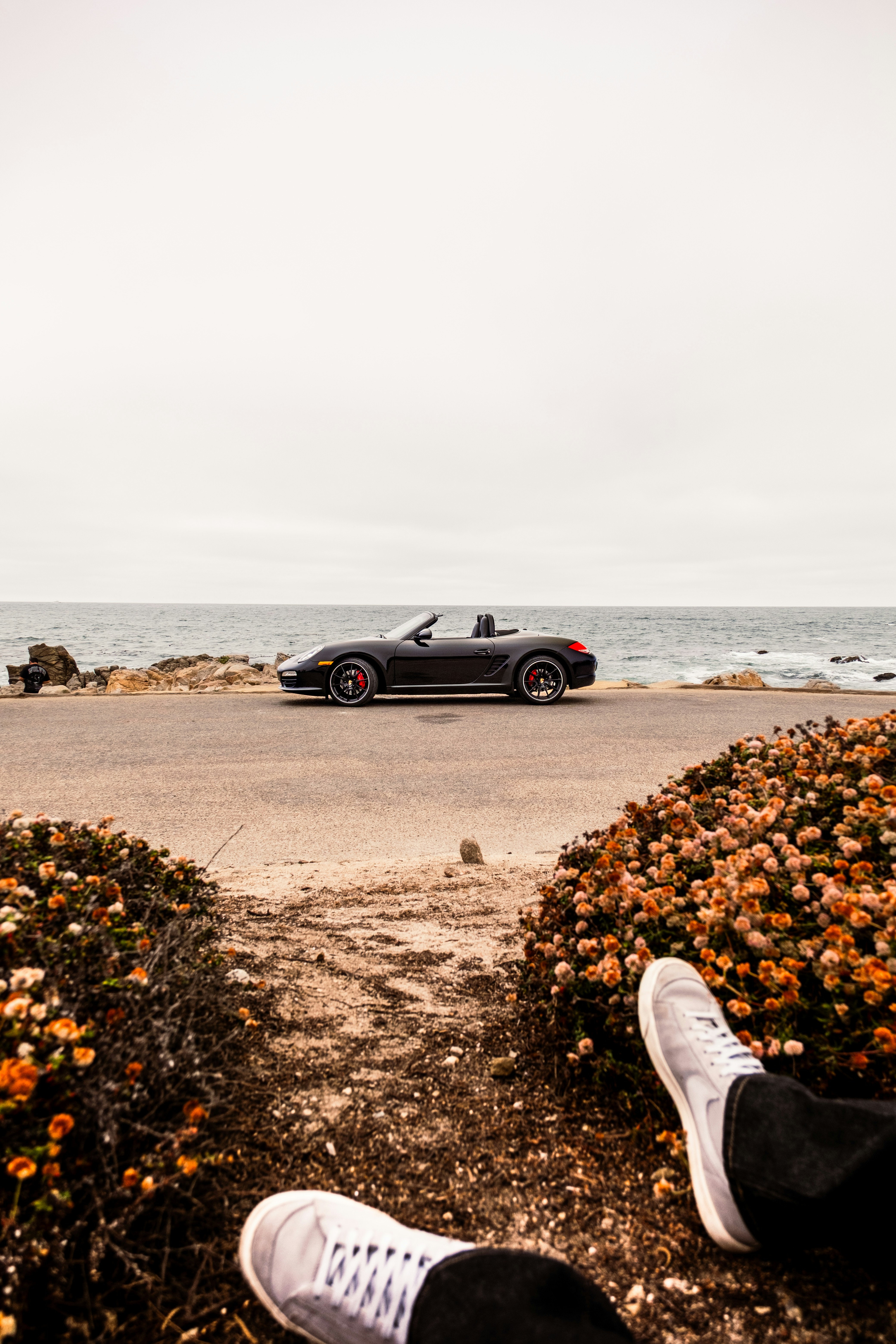 A Black Convertible Sports Car Parked On A Coastal Road By The Ocean HD mobile wallpaper