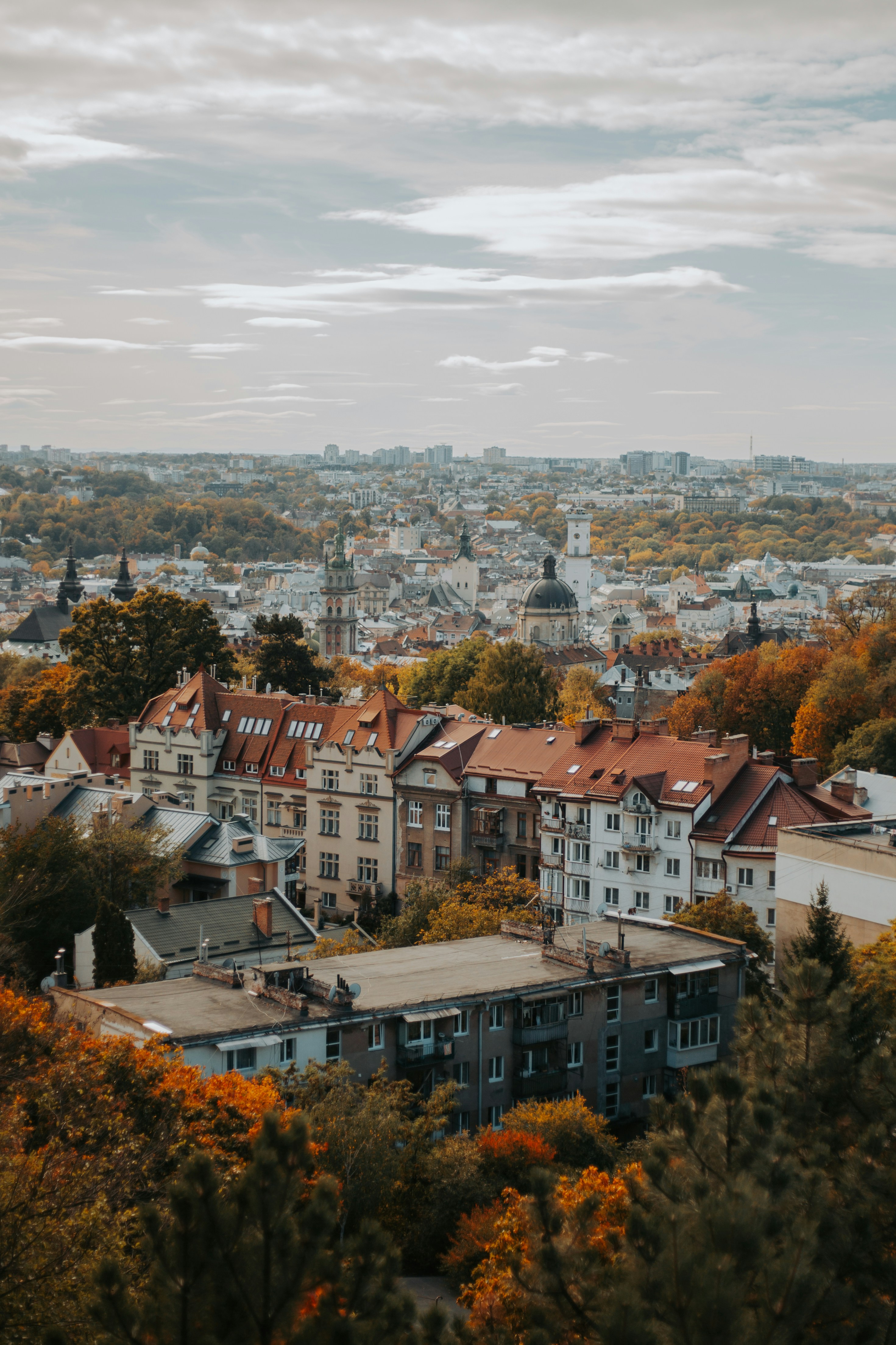 An Aerial View Of Lviv With Historic Buildings And Autumn Trees Under A Cloudy Sky HD mobile wallpaper