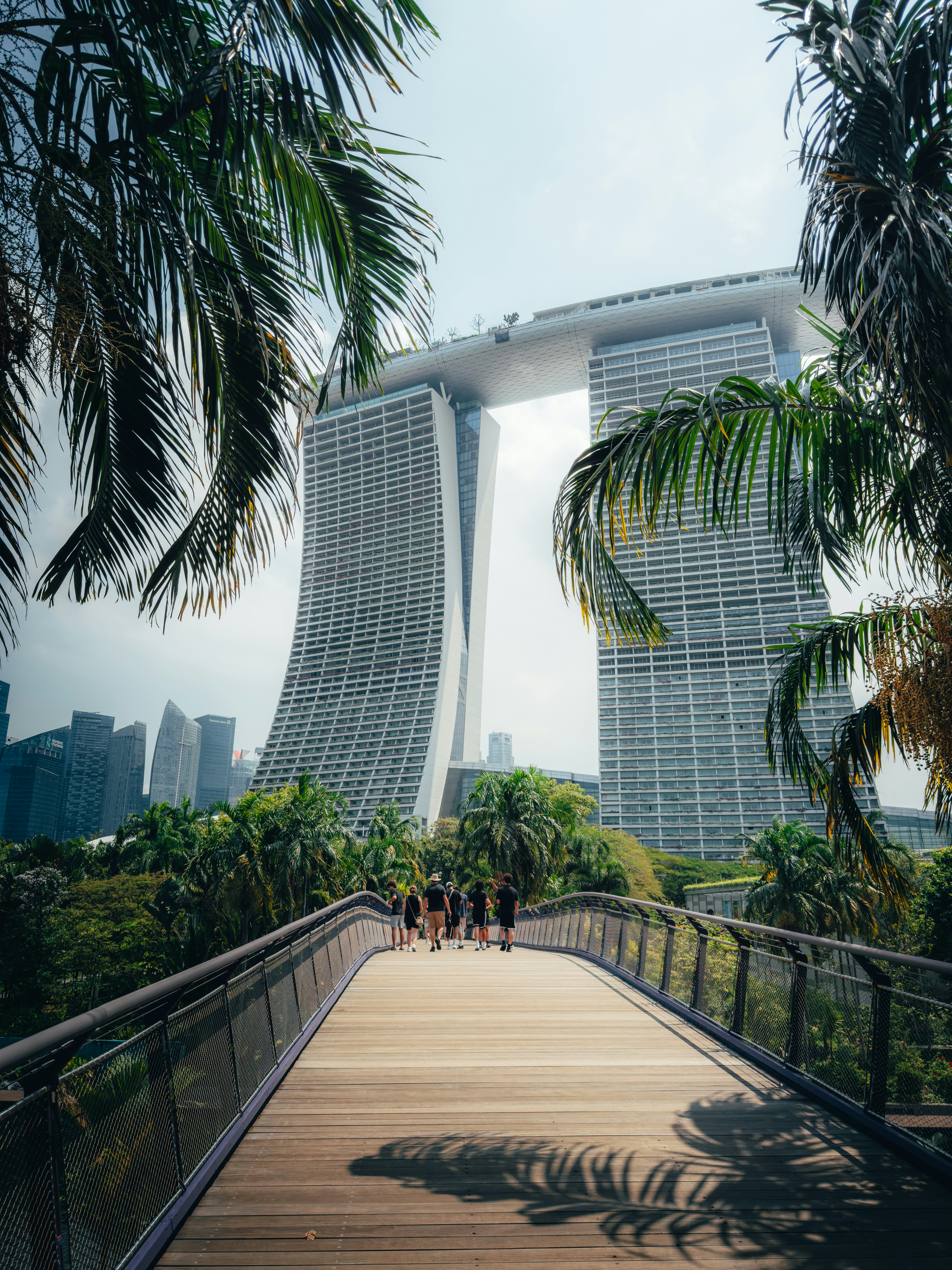 A Group Of People Walking On A Wooden Bridge Toward Marina Bay Sands In Singapore HD mobile wallpaper