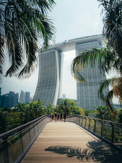 A Group Of People Walking On A Wooden Bridge Toward Marina Bay Sands In Singapore wallpaper preview