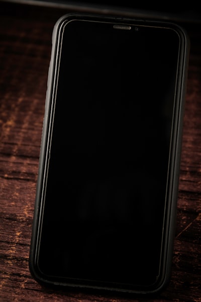 A Black Cell Phone Sitting On Top Of A Wooden Table wallpaper preview