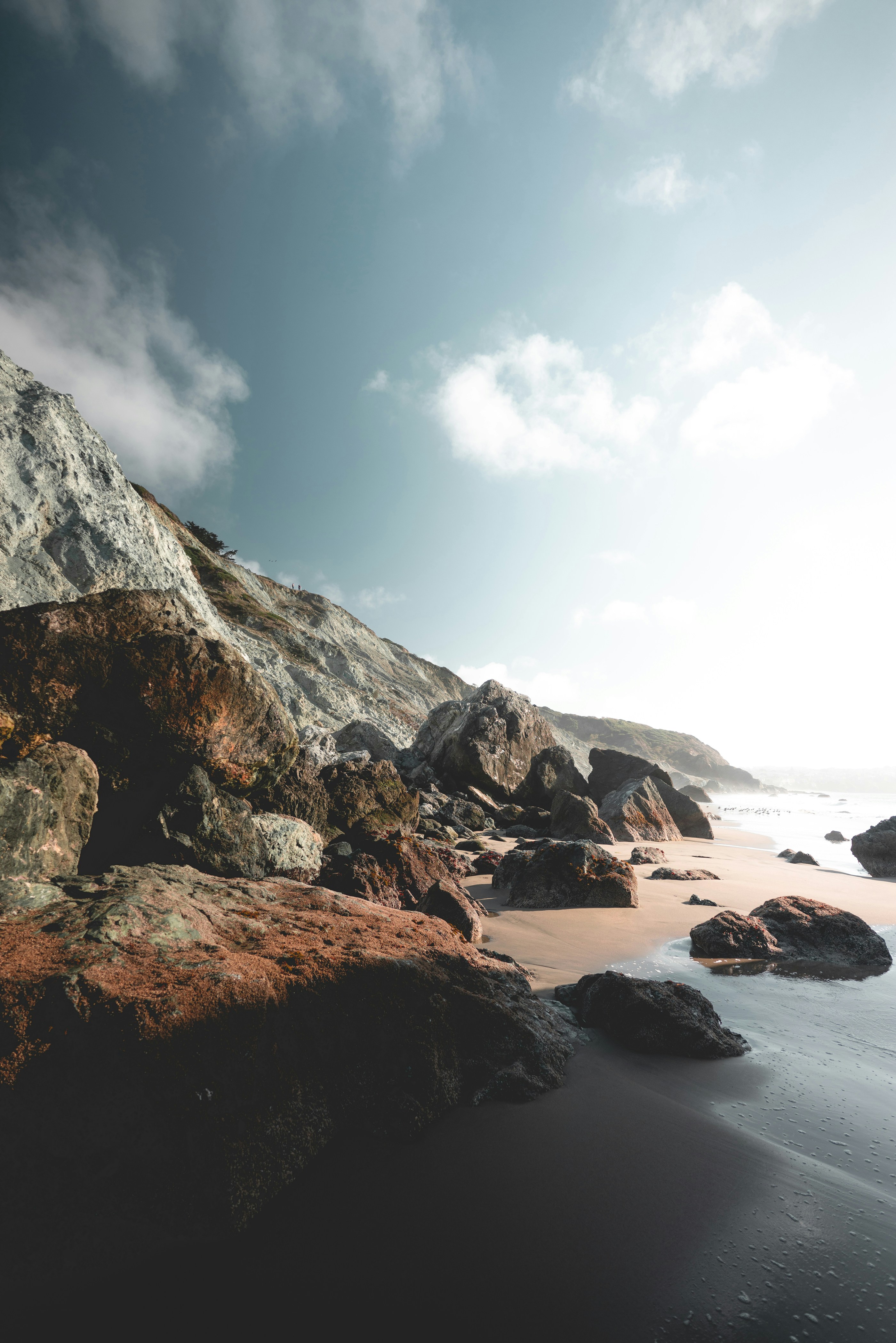 A Beach With Rocks And Water Under A Cloudy Sky HD mobile wallpaper